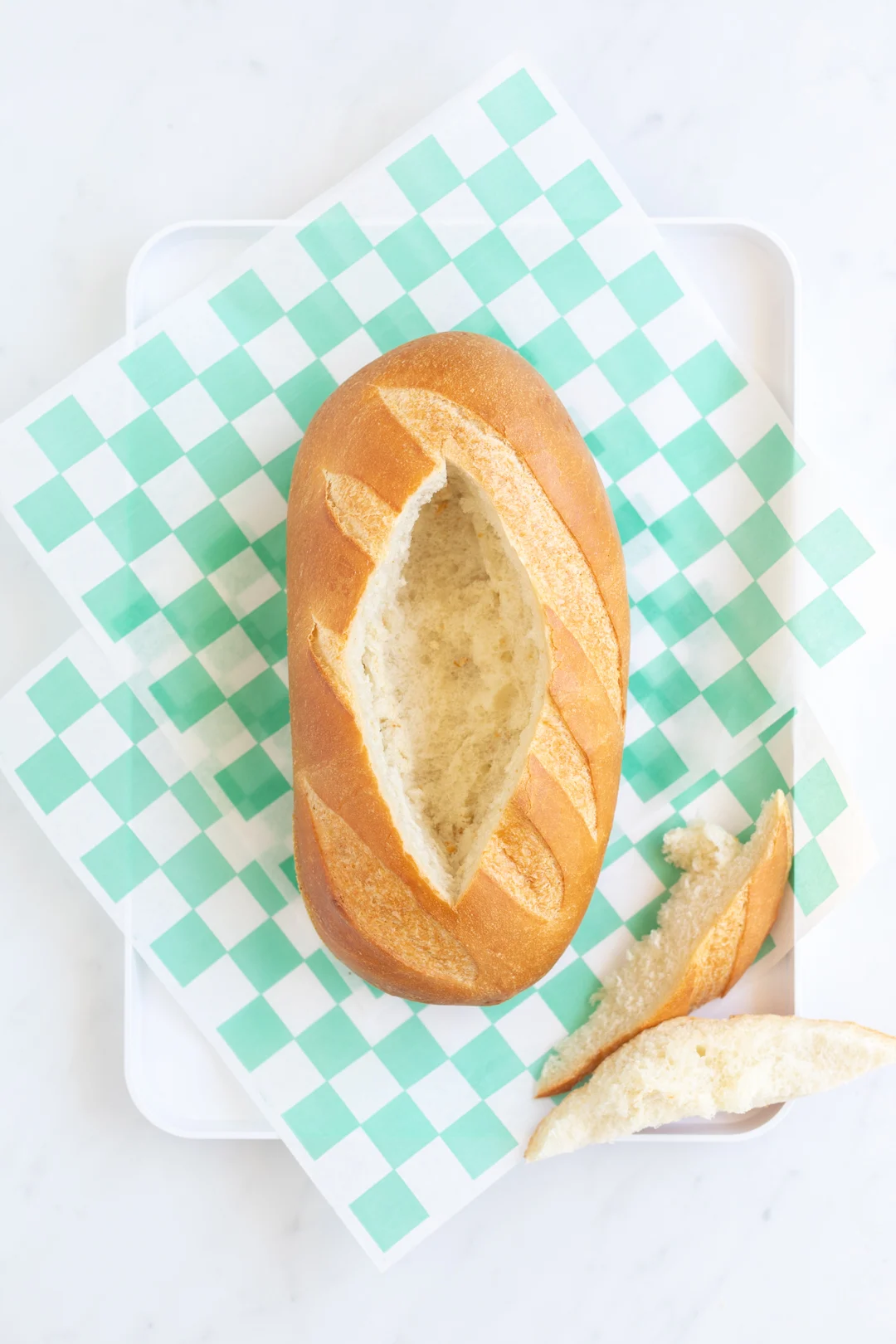 center cut out of oval shaped bread loaf to prepare to make football dip in bread bowl
