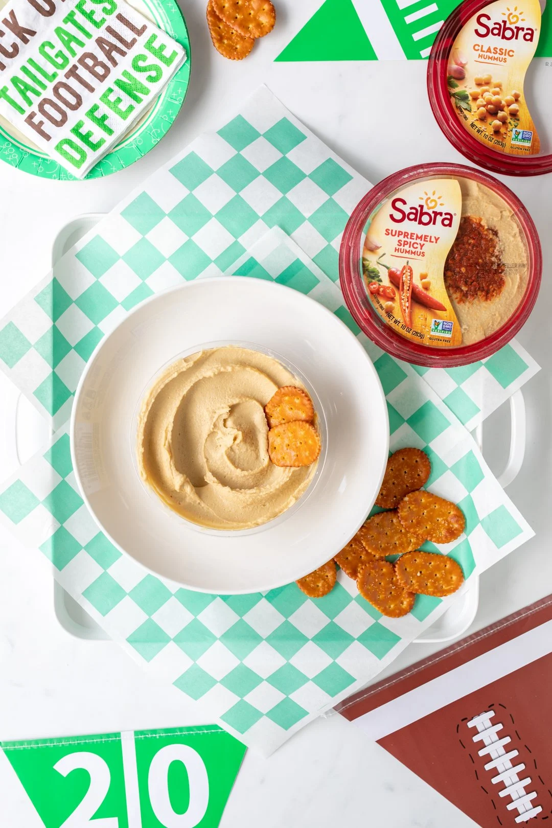 hummus in a bowl along with pretzel crackers for game day