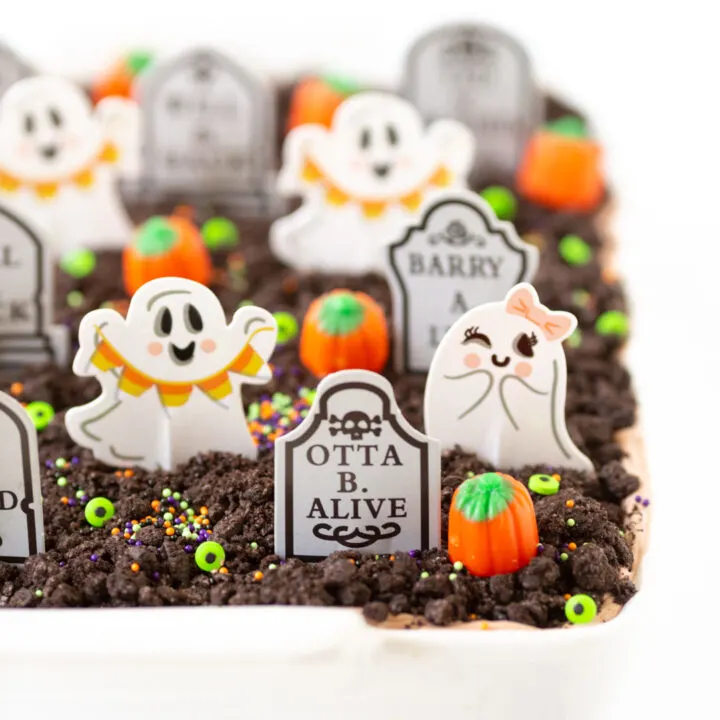 graveyard chocolate layered cake topped with crushed oreos, candy eyes, grave cupcake toppers, sprinkles