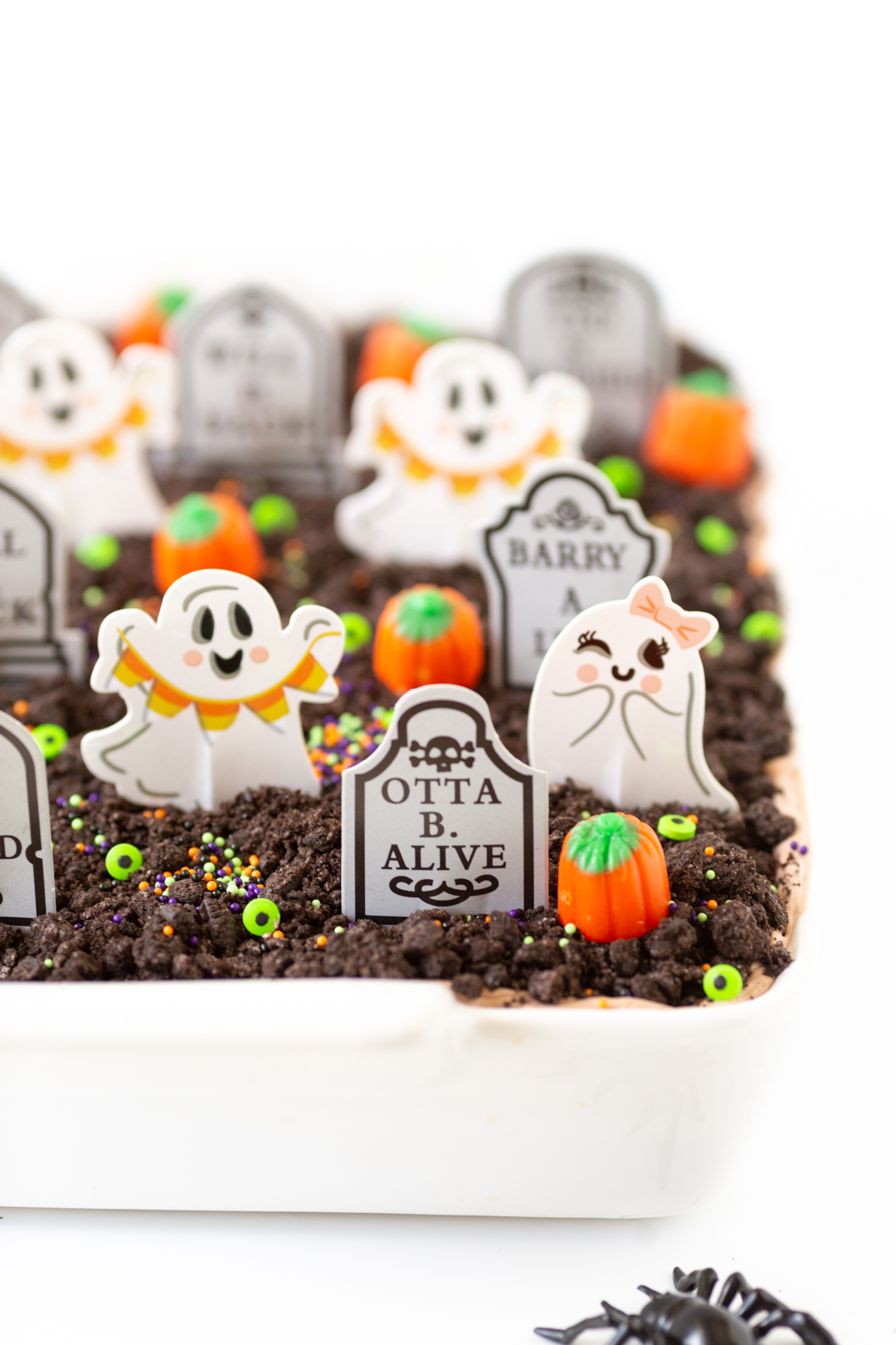graveyard chocolate layered cake topped with crushed oreos, candy eyes, grave cupcake toppers, sprinkles