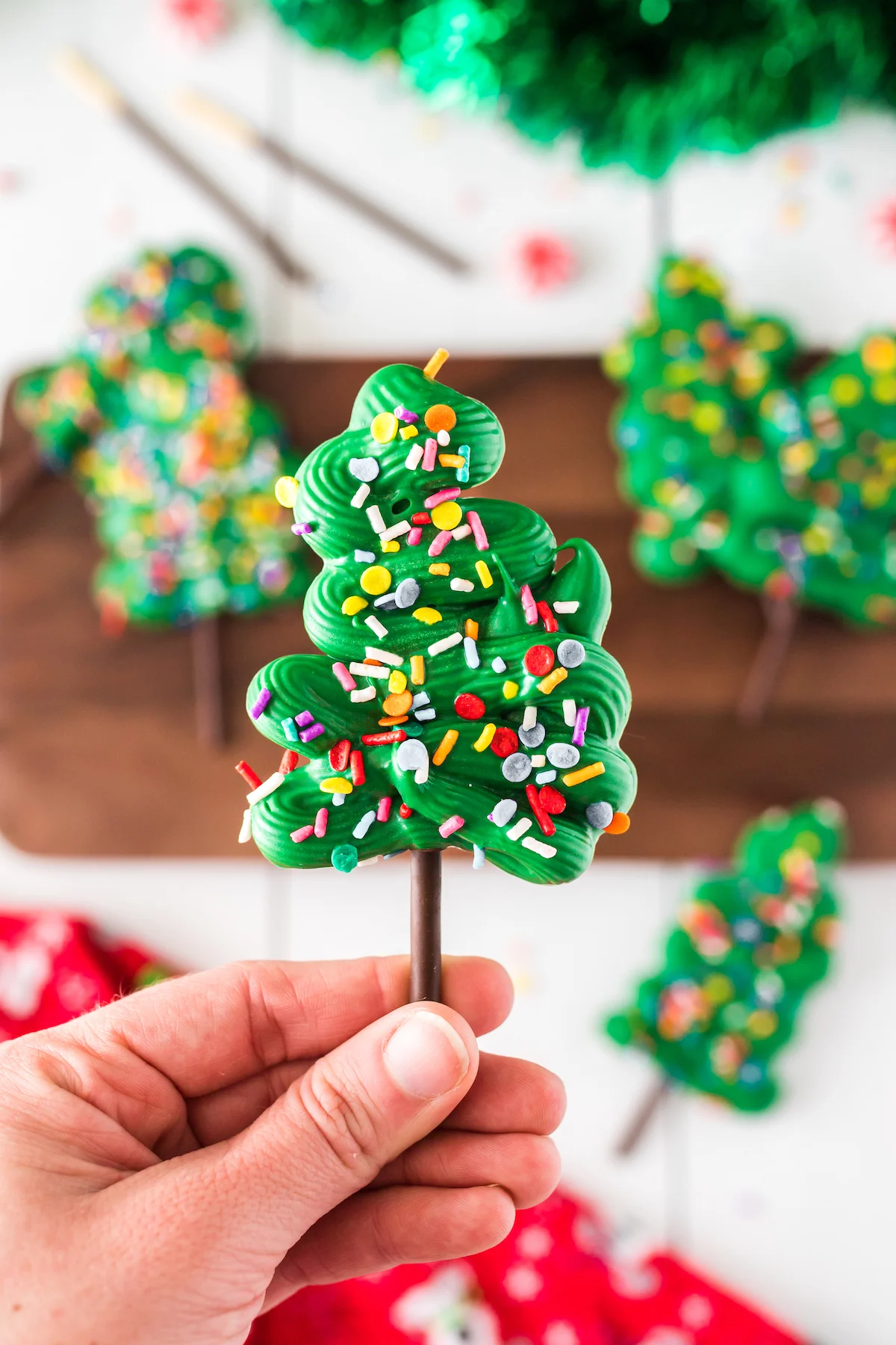 woman holding pocky christmas tree treat made with chocolate and sprinkles