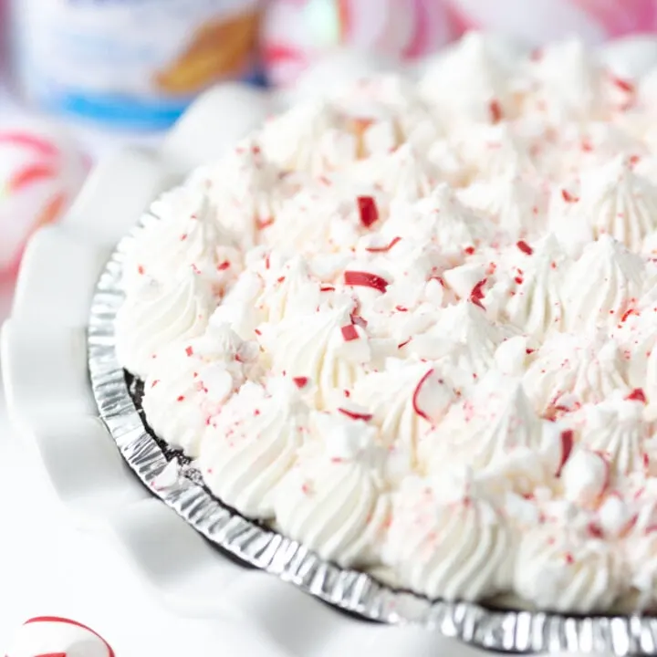 Pretty peppermint pie in a white ruffled pie dish and crushed peppermint on top.