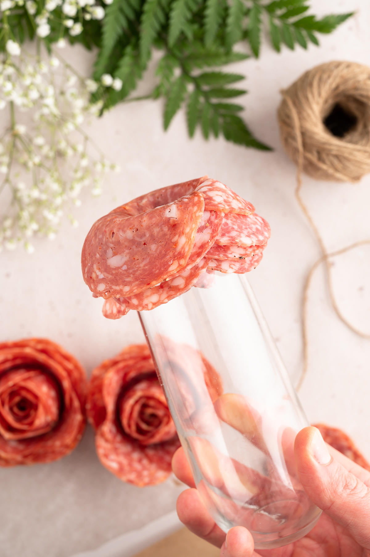 showcasing layers of salami on a glass to make salami roses