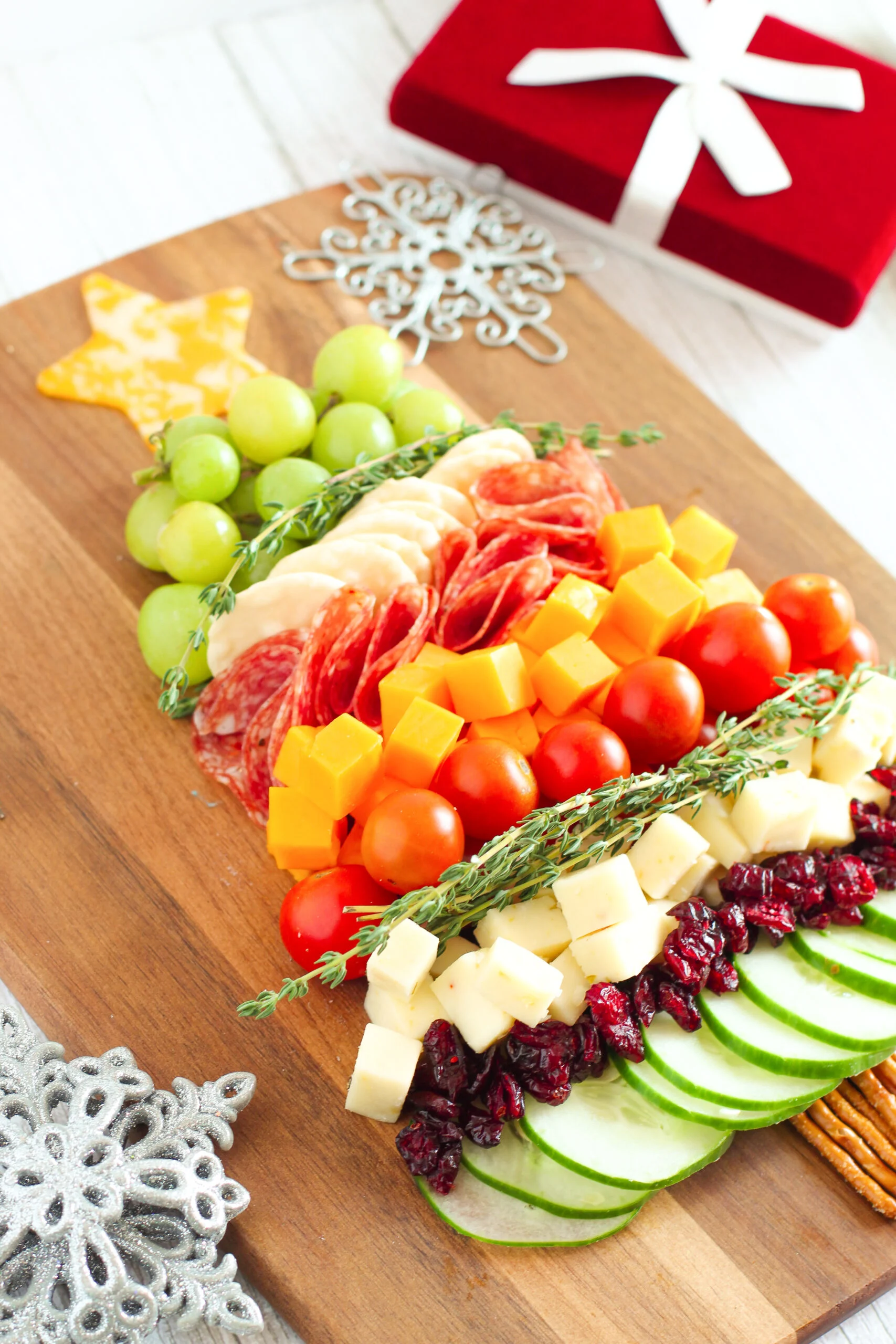 festive christmas tree appetizer with layers of grapes, cheeses, meats, cherry tomatoes.