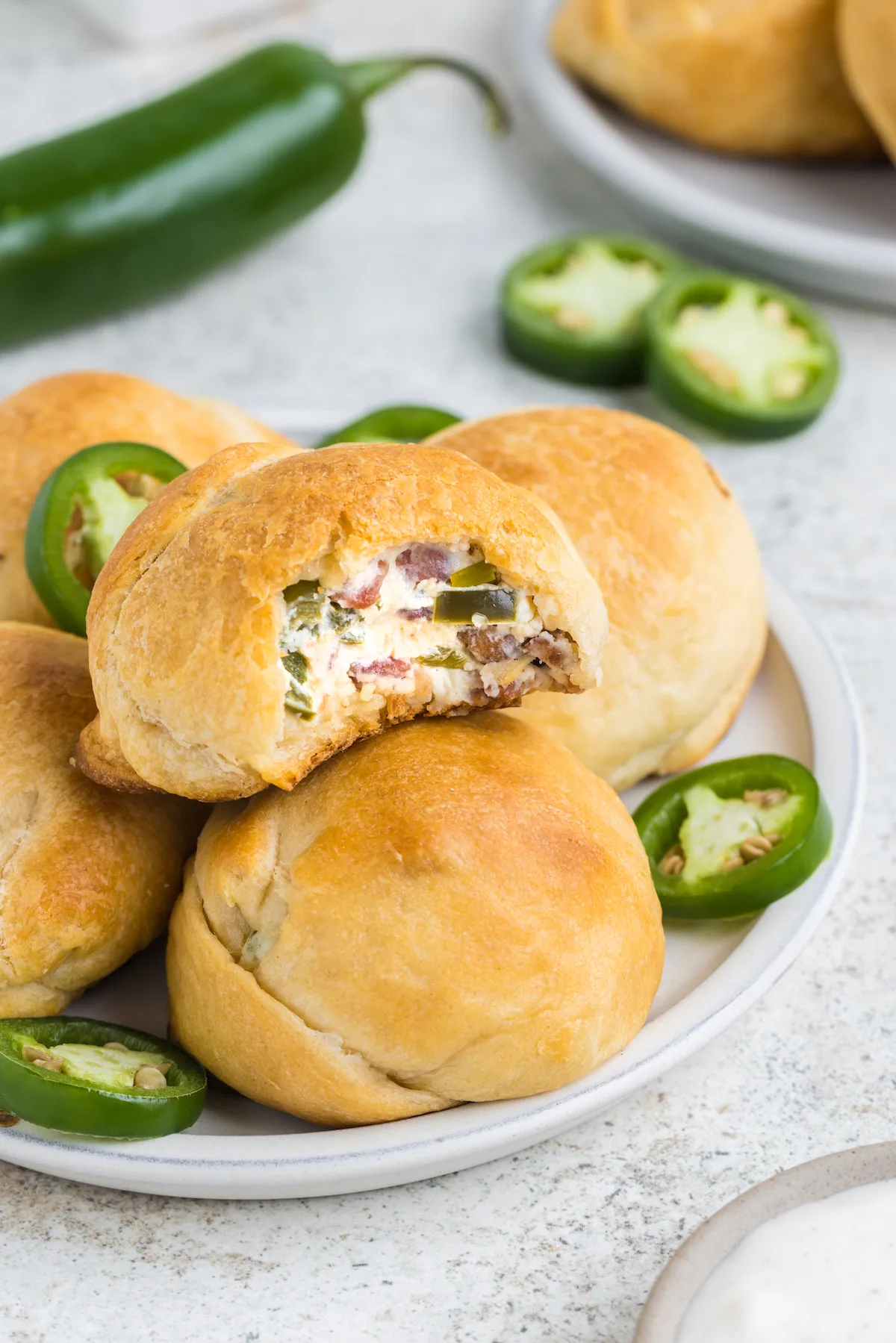 stacked jalapeno rolls on a plate with jalapeno pepper slices