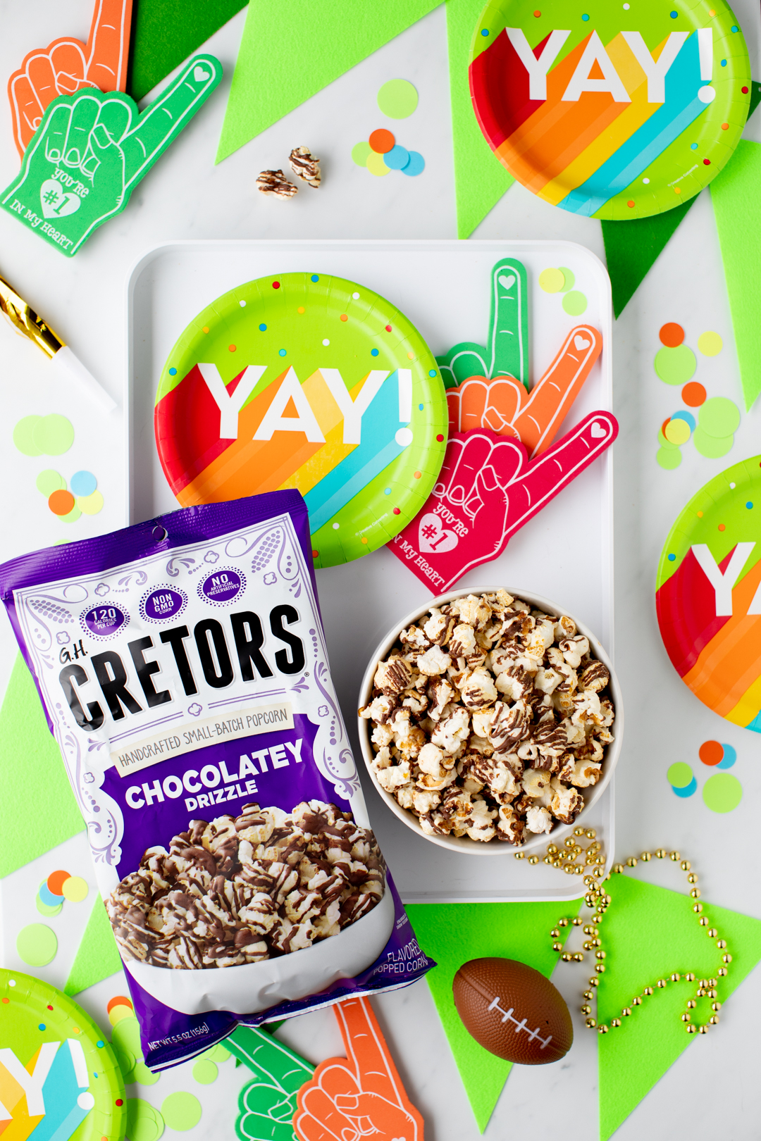 chocolatey drizzle popcorn bag set on a vibrant rainbow themed football game day table