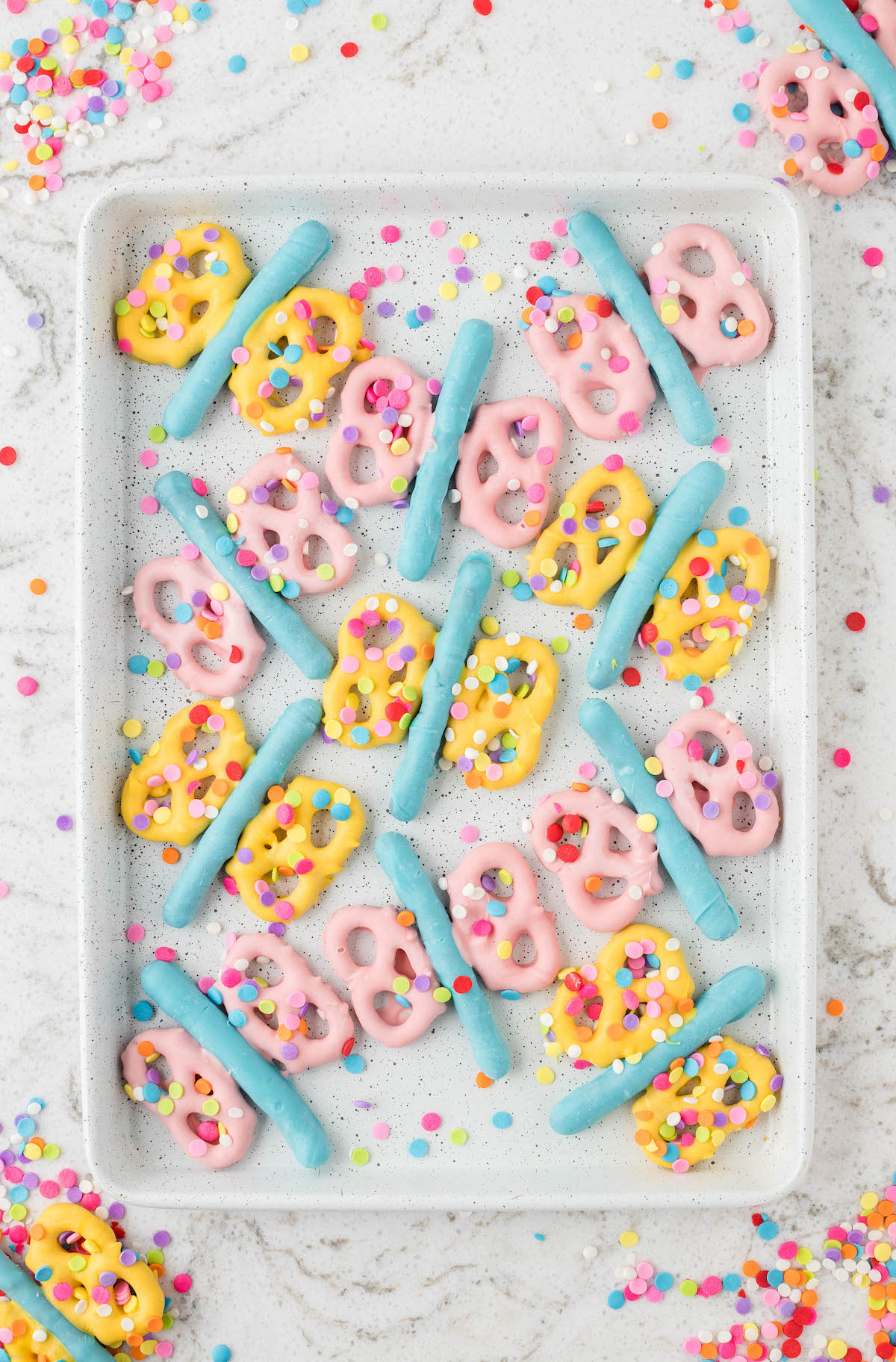 lots of pastel butterfly pretzels set out on a white baking tray