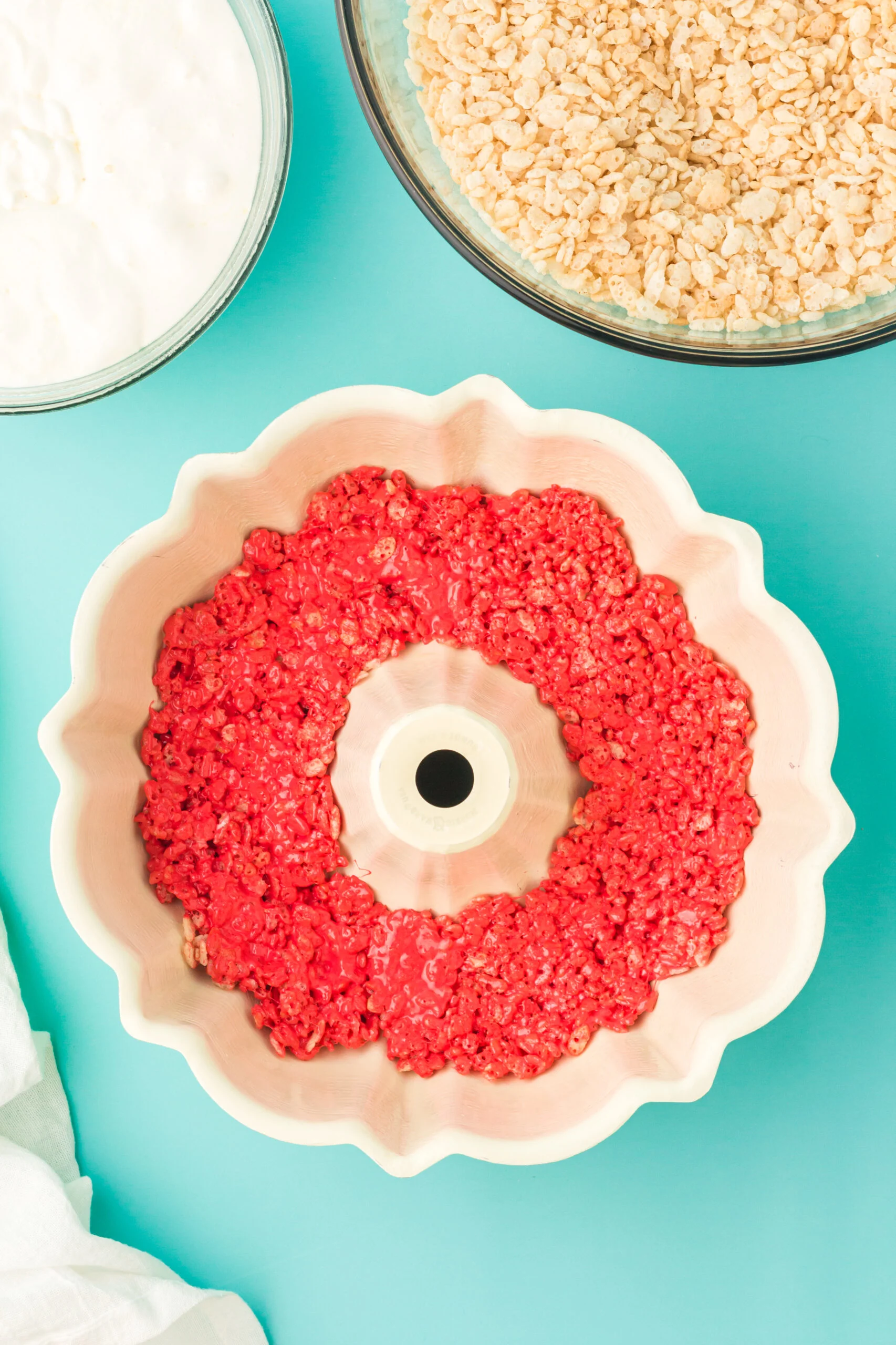 a red layer of rice krispies treats pressed into base o a bundt pan to make a rainbow cake