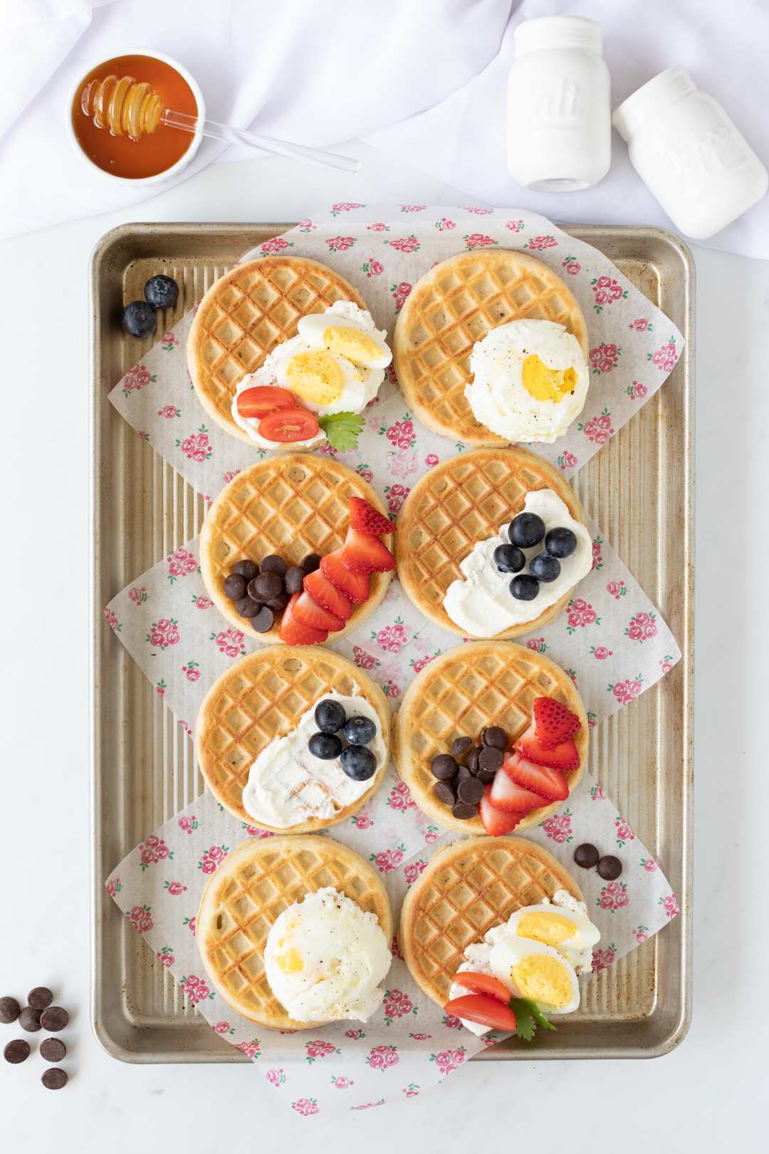 adding toppings to eggo waffles on a baking sheet