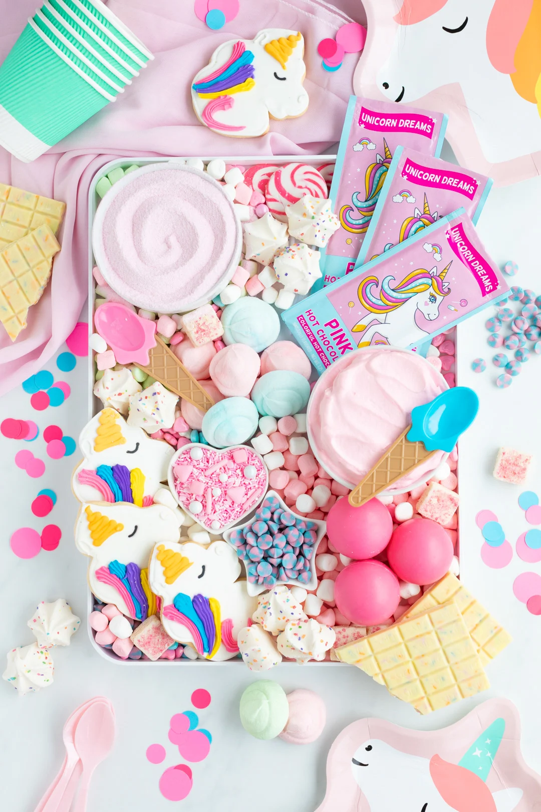 over the top photo of a unicorn themed hot cocoa board filled with the best unicorn and pink hot cocoa and hot cocoa toppings. hot pink cocoa melts, marshmallows.