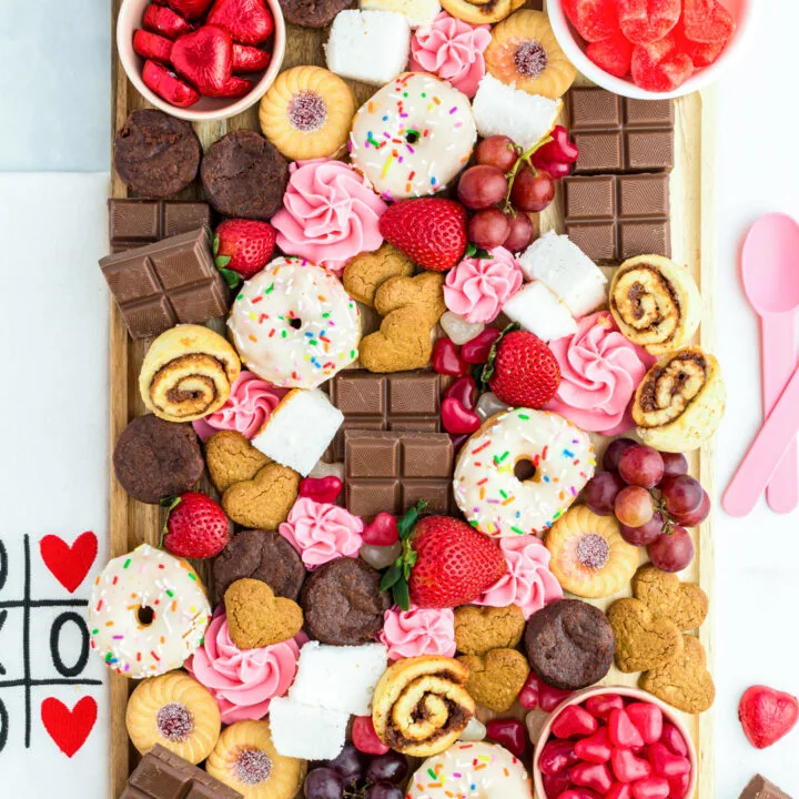 gorgeous dessert charcuterie board with chocolate, heart candies, cinnamon rolls, cookies.