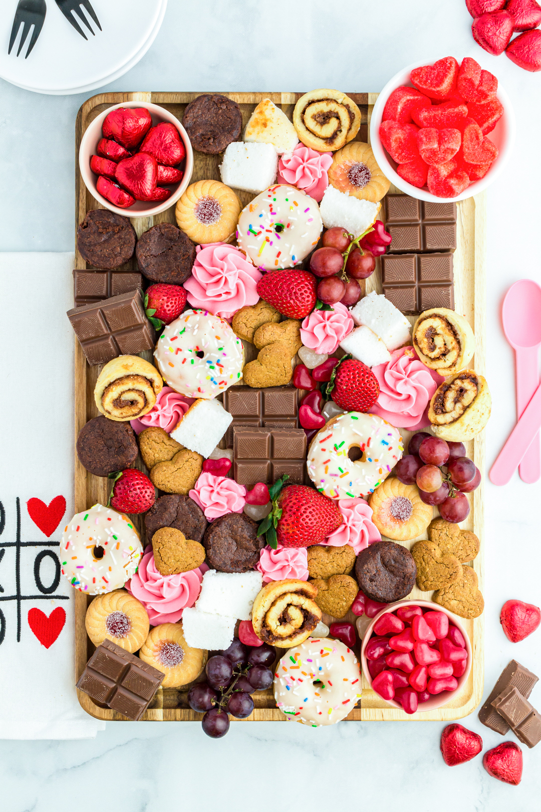 gorgeous dessert charcuterie board with chocolate, heart candies, cinnamon rolls, cookies. 