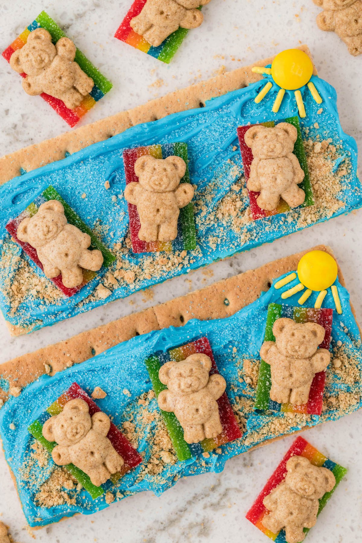 up close over the top view of beach themed graham crackers with teddy grahams and a candy sun. cute kid snack.