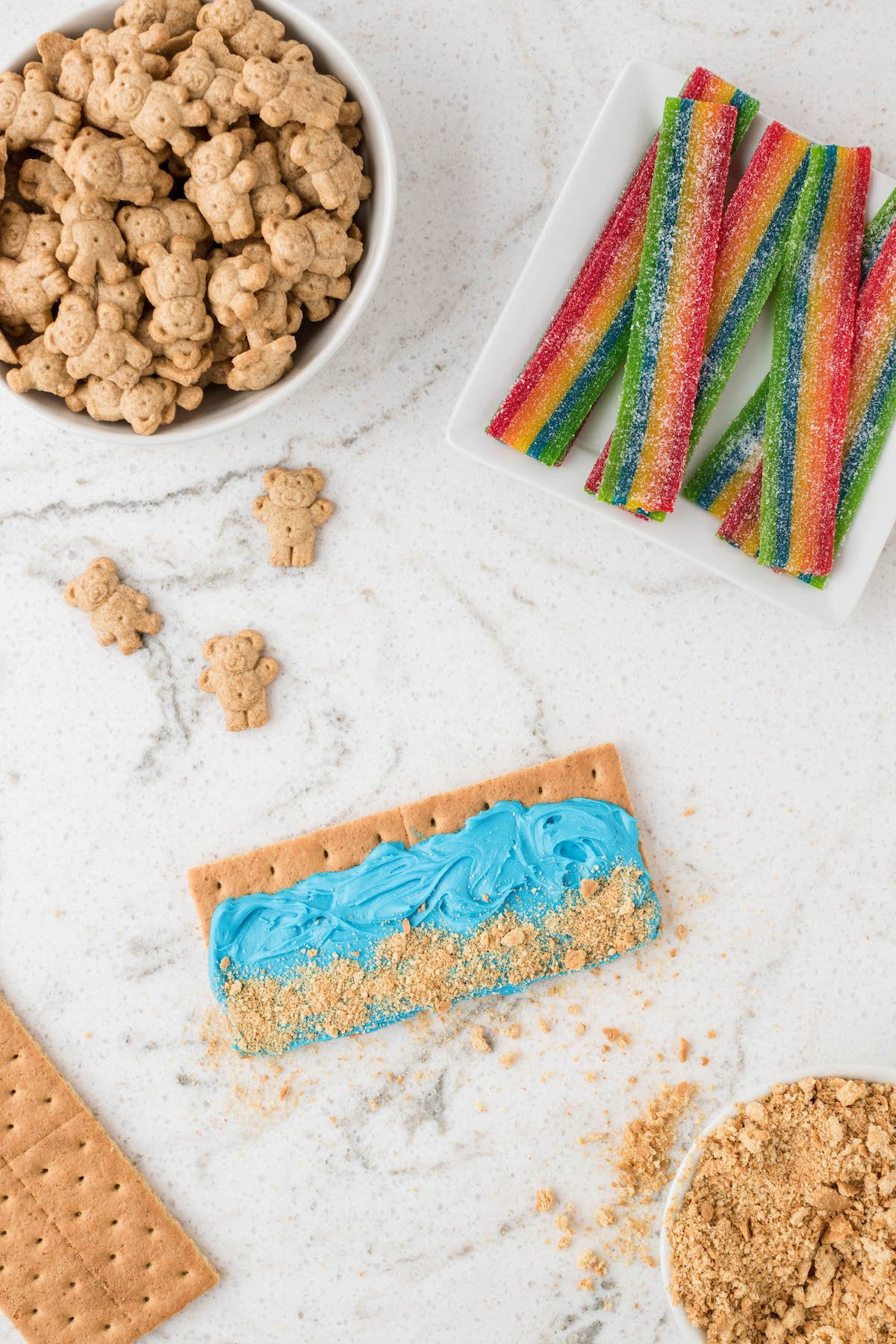 placing crushed graham cracker onto blue frosting