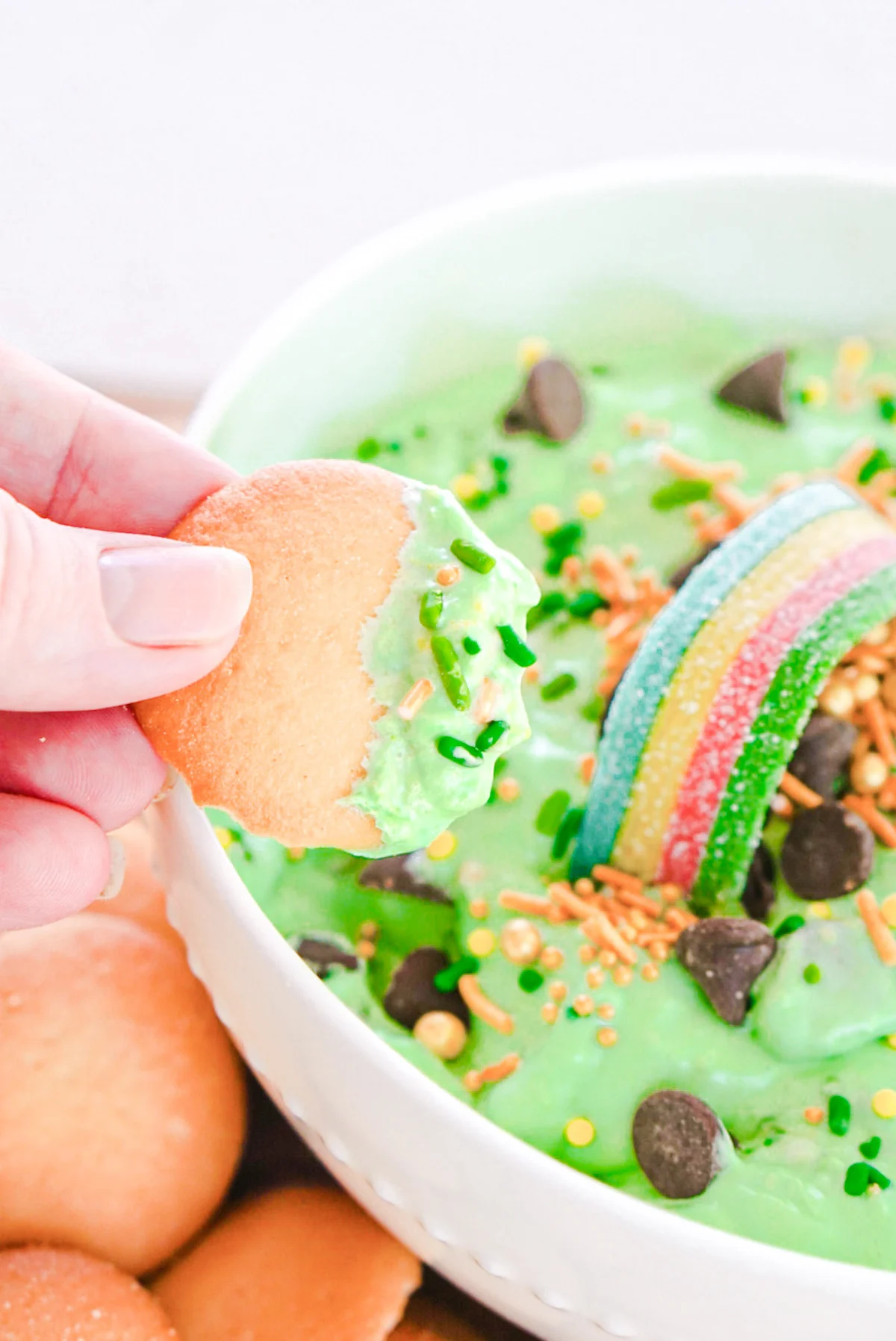 dipping a nilla wafer into a bowl of st. patrick's day booty dip.