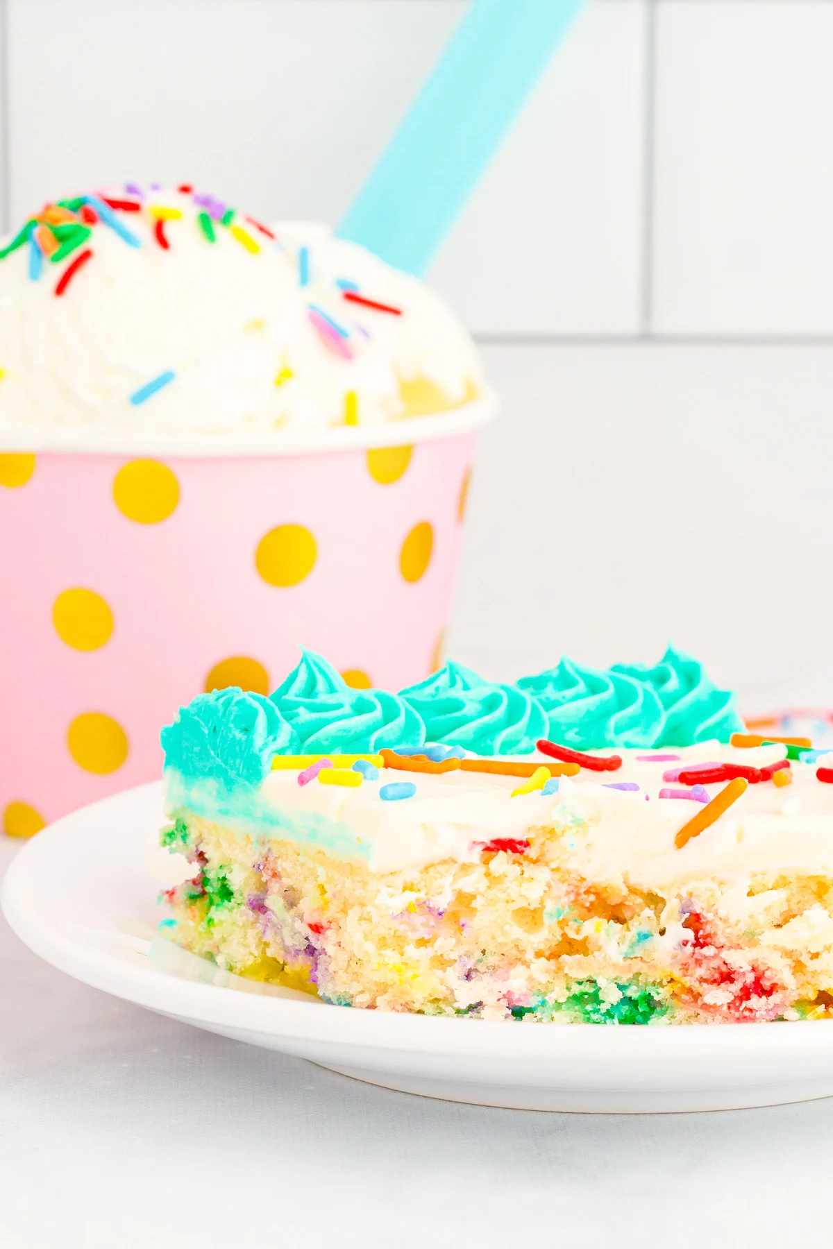 confetti birthday cake slice with ice cream in background
