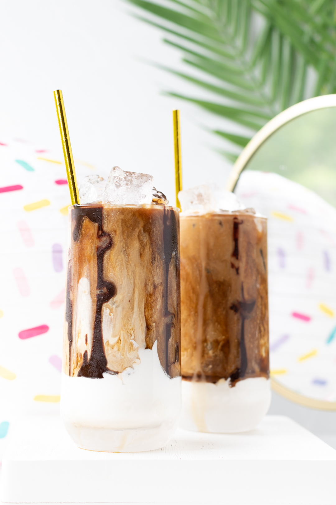 up close view of upside down iced coffee with chocolate drizzle and gold paper straws