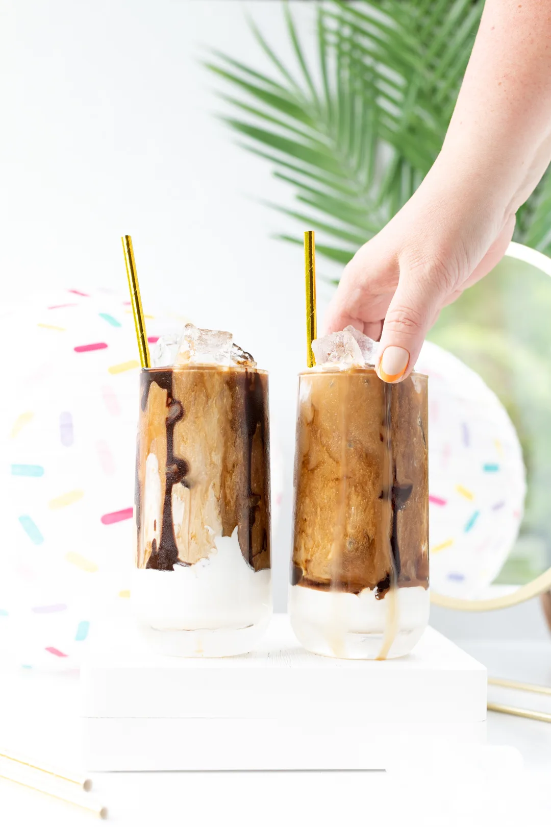 woman grabbing iced coffee glass with chocolate drizzle