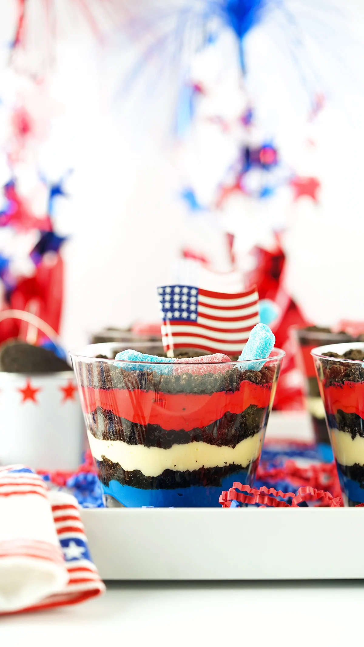 gorgeous red, white and blue dessert dirt cups served on a decorated white tray.