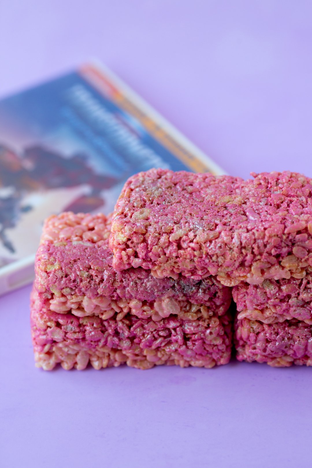 angled down view of neon pink rice krispie bars with transformer dvds behind it