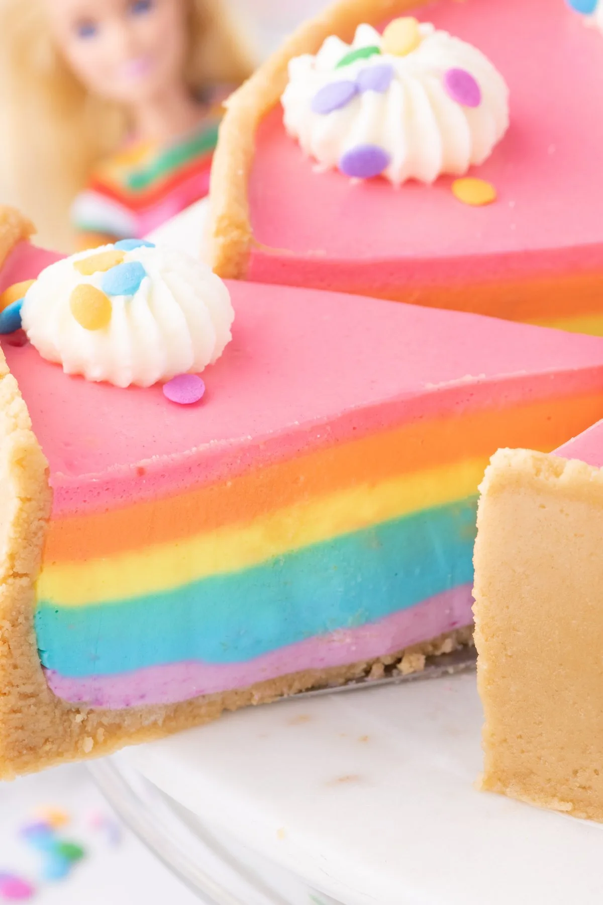 slice being removed from barbie rainbow cake