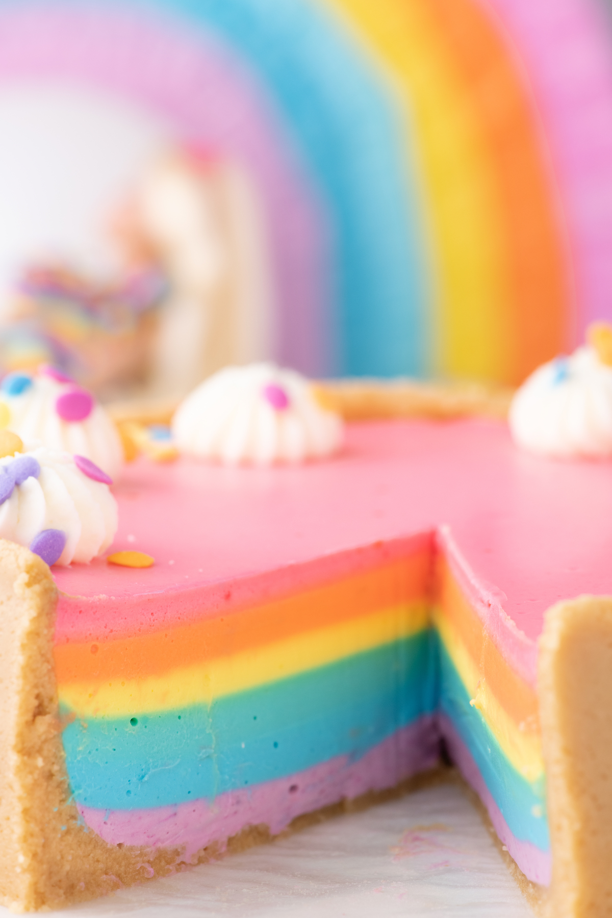 slice removed from rainbow cheesecake to reveal pretty colored layers