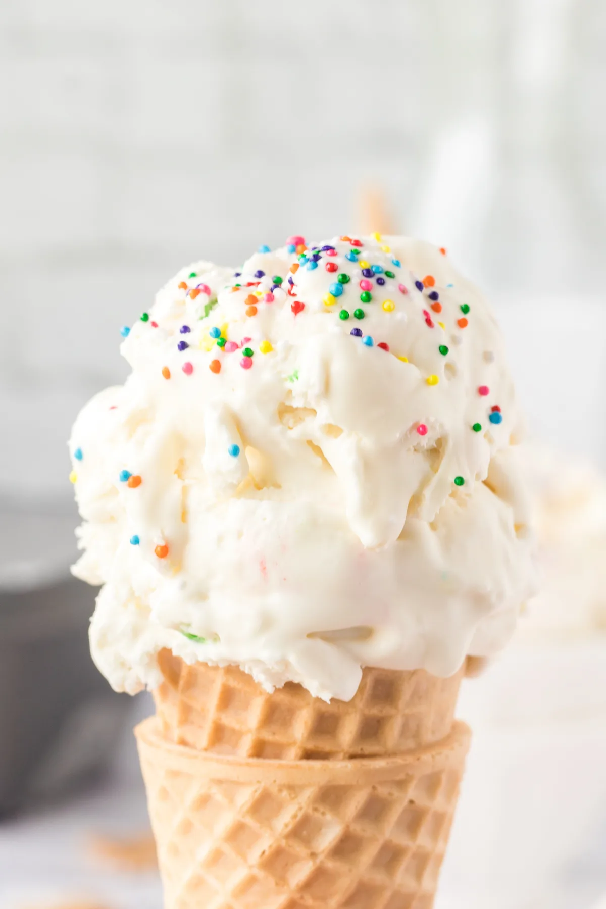 up close view of ice cream scoops in a cone topped with sprinkles
