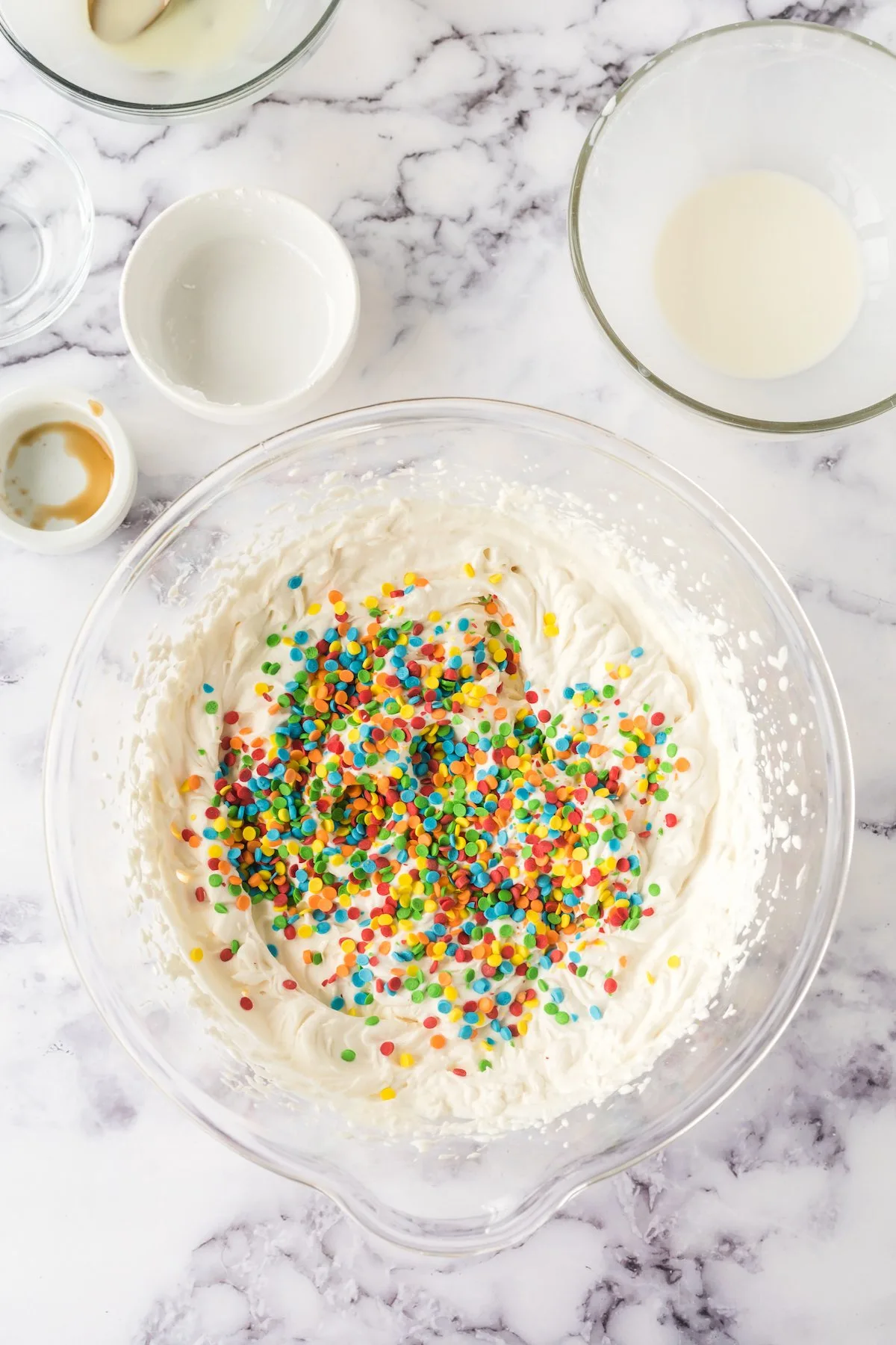 sprinkles added to homemade funfetti ice cream mixture in bowl