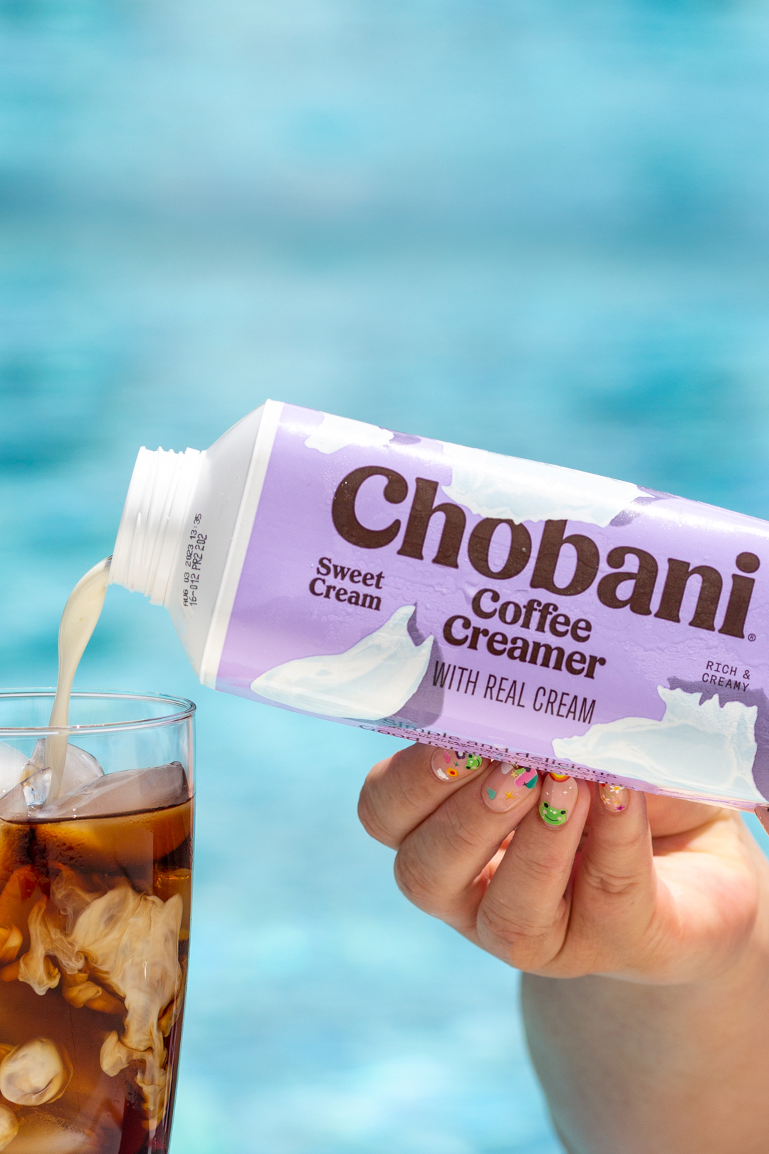 pouring chobani creamer into iced coffee at the pool