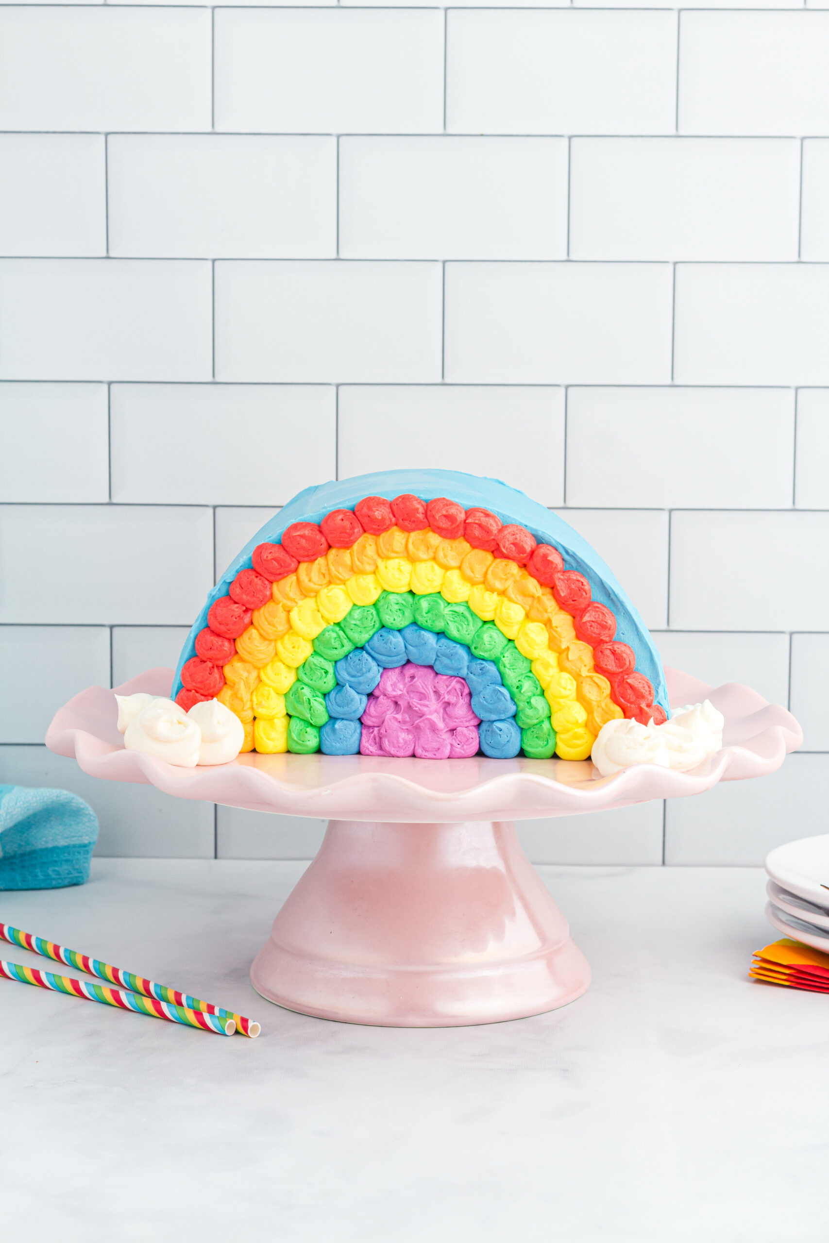 pretty rainbow cake with frosting set on a pretty cake stand