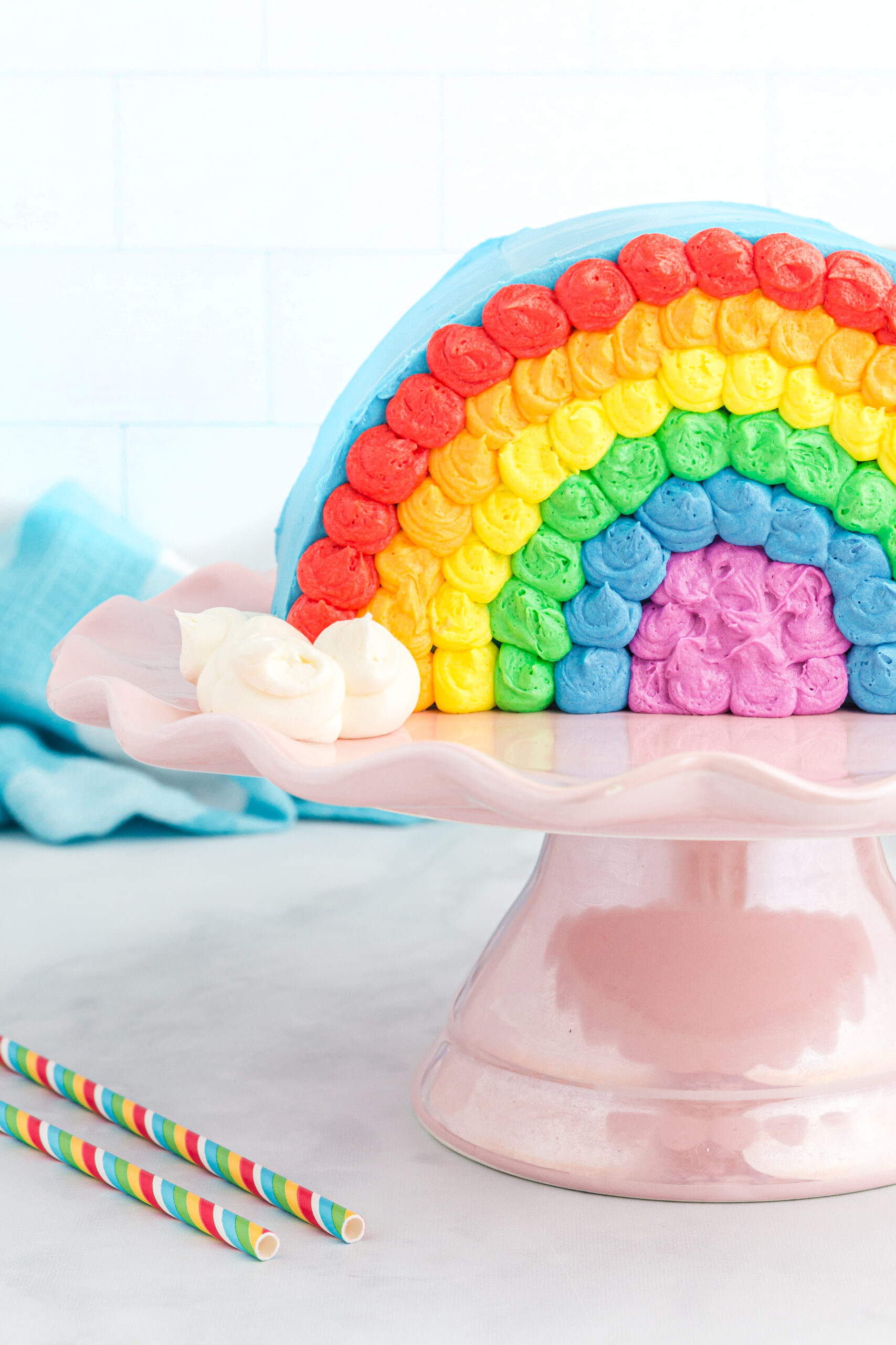 pretty rainbow cake served on a shiny pink cake stand.