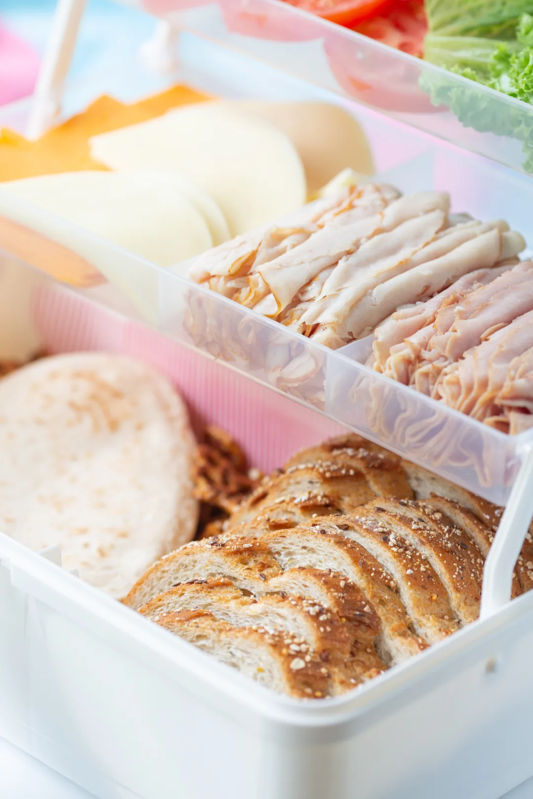lunch meats and deli cheeses and bread slices set up inside of a sandwich tackle box