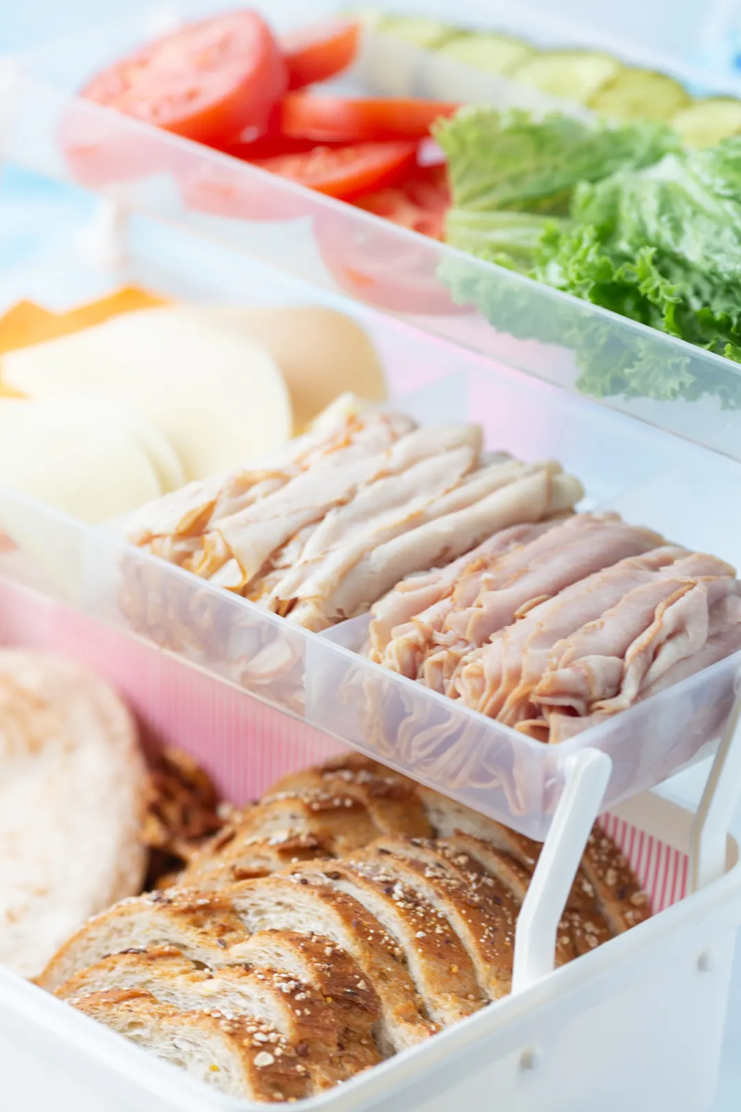 view inside of a Sandwich Tackle Box to showcase sandwich fixings including bread slices, lunch meats, sliced cheeses and vegetables.a