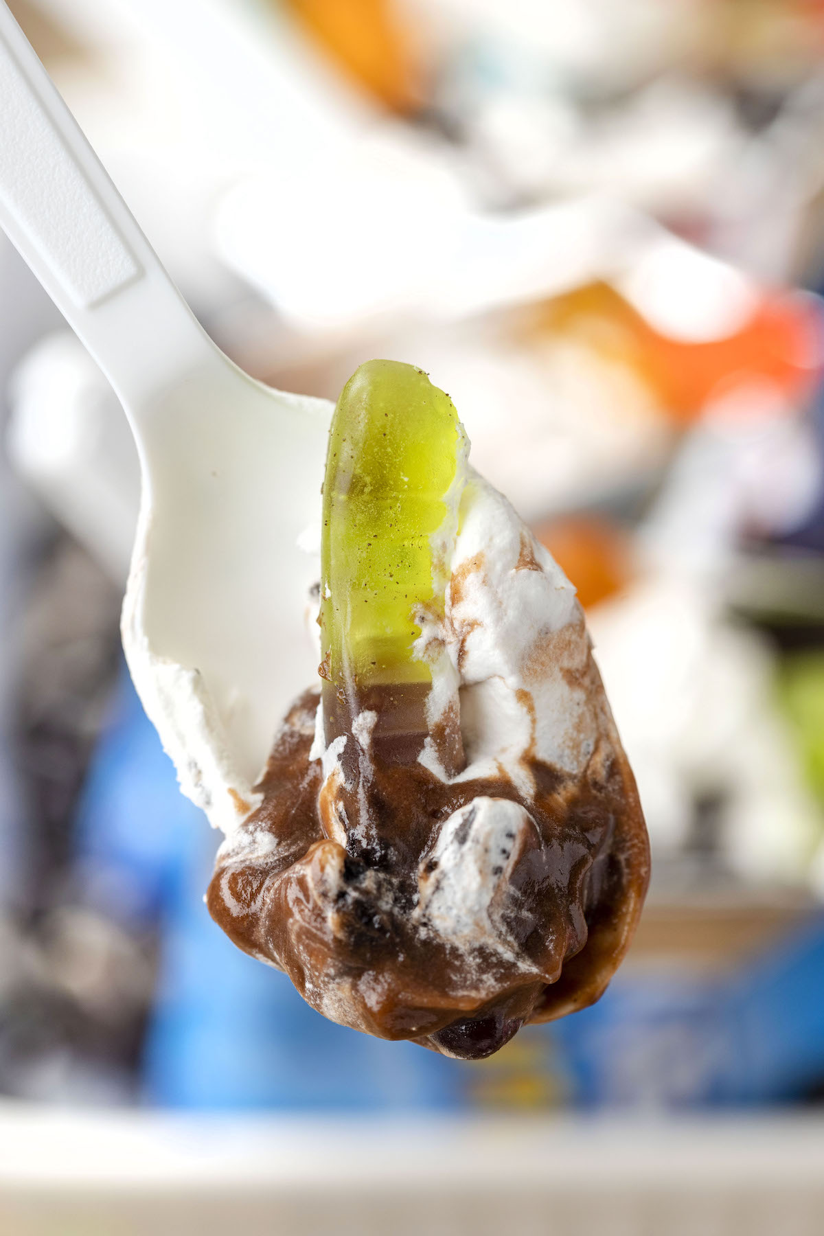 up close view of spoon with gummy worm, chocolate pudding, crushed oreo and whipped topping,