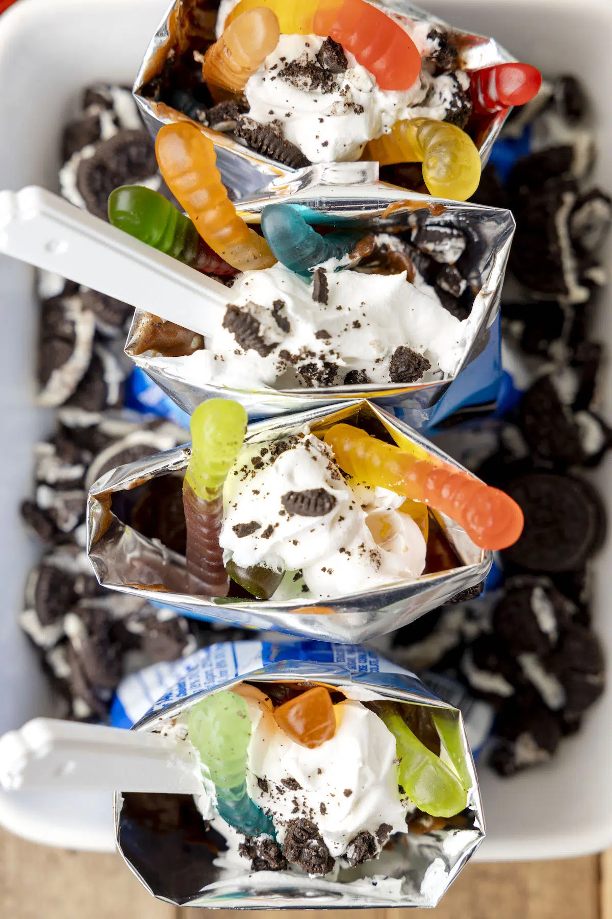 over the top walking dirt cup desserts with gummy worms, whipped cream and gummy worms.