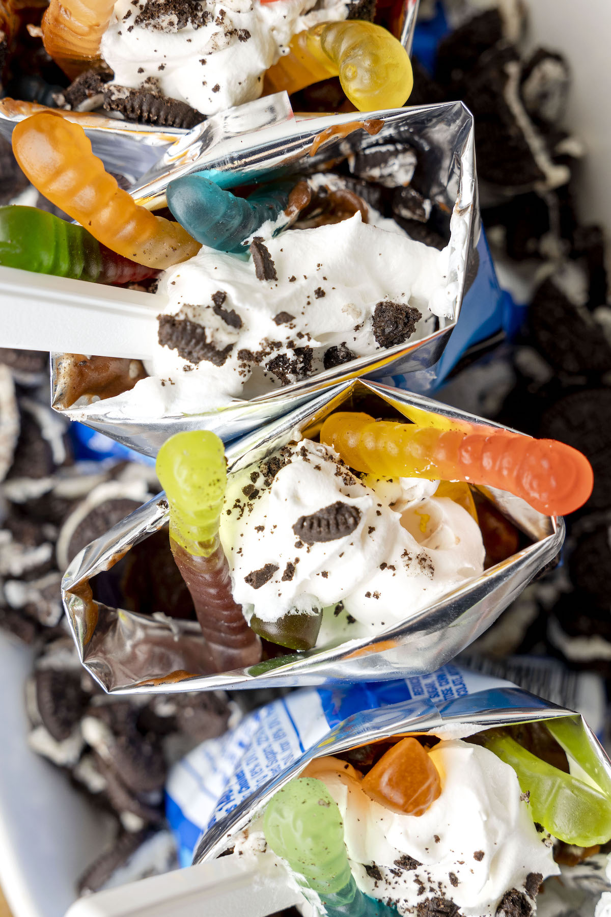 up close and over the top photo of walking dirt cup desserts with gummy works and crushed oreos.