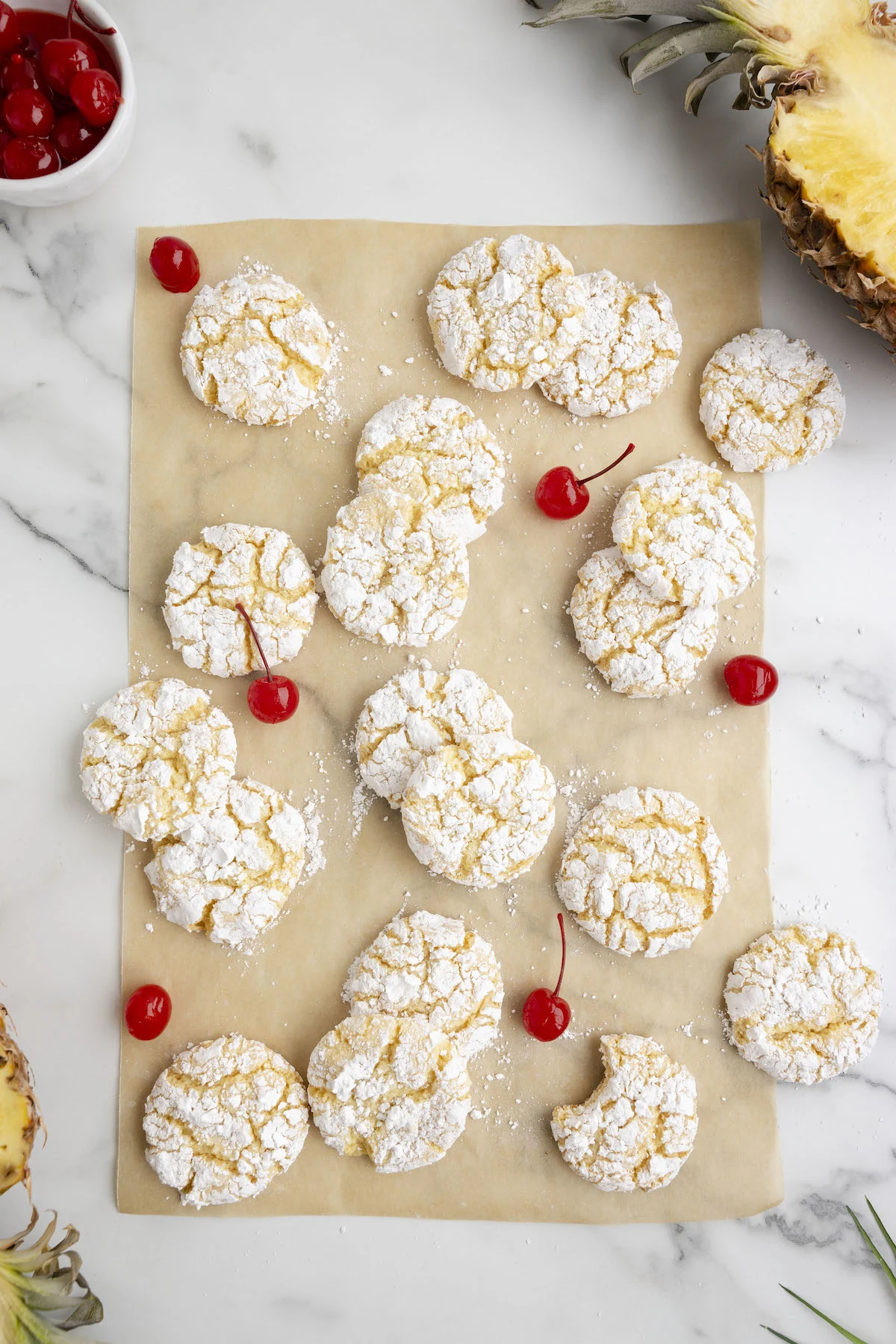 pineapple cookies spread on brown parchment paper with maraschino cherry garnish