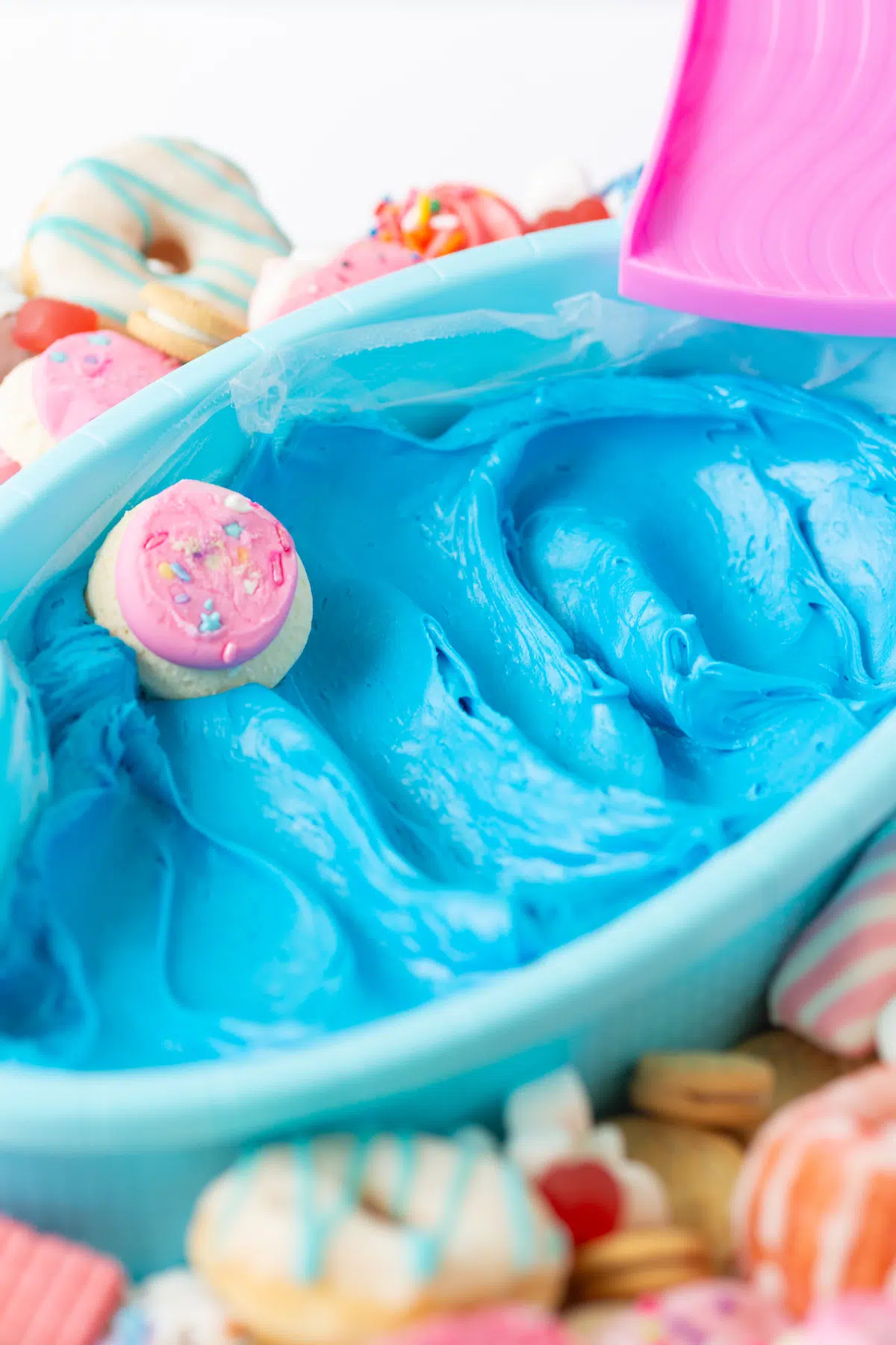 cookie being dipped into Barbie blue pool frosting dip