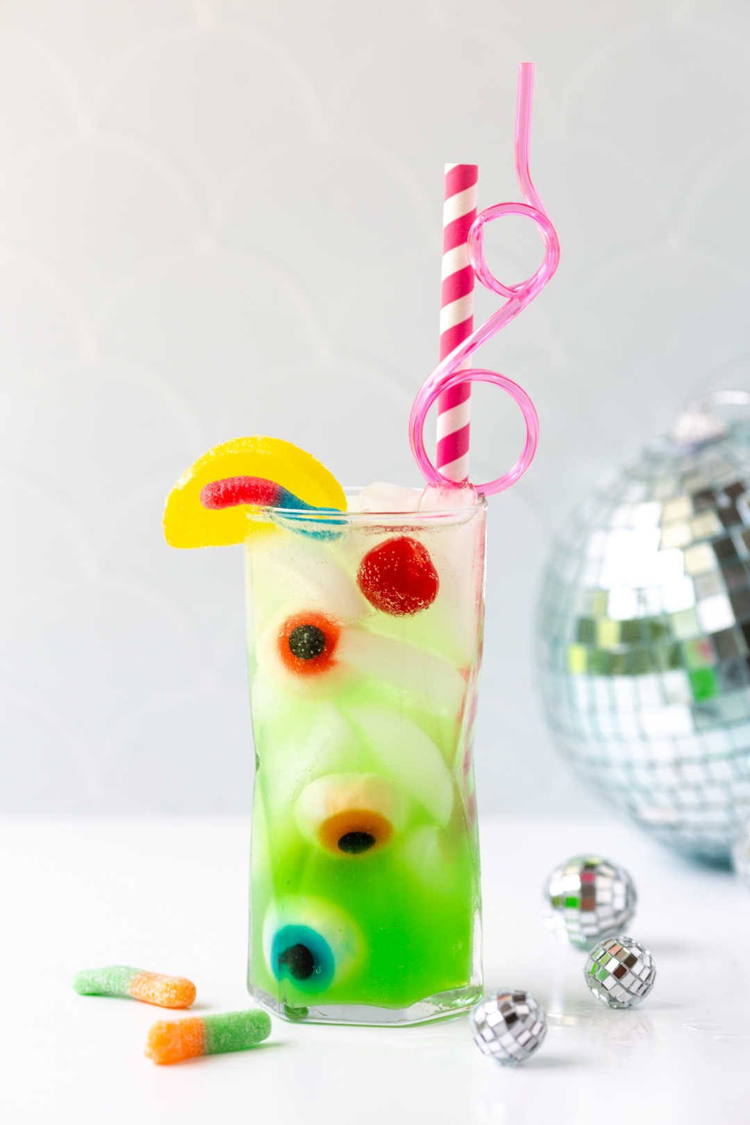 green tinted ghoul juice  inspired by monster high: the movie with fun pink straws, gummy eyeballs, gummy worms and candy lemon.