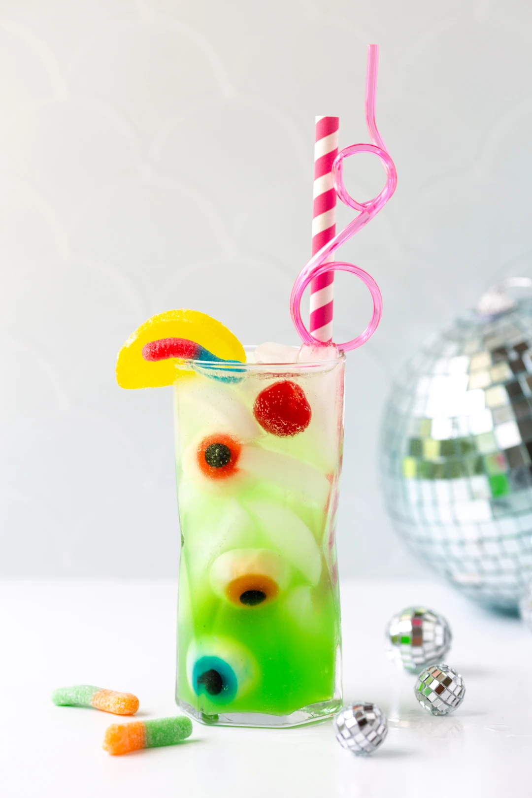 green tinted ghoul juice  inspired by monster high: the movie with fun pink straws, gummy eyeballs, gummy worms and candy lemon.