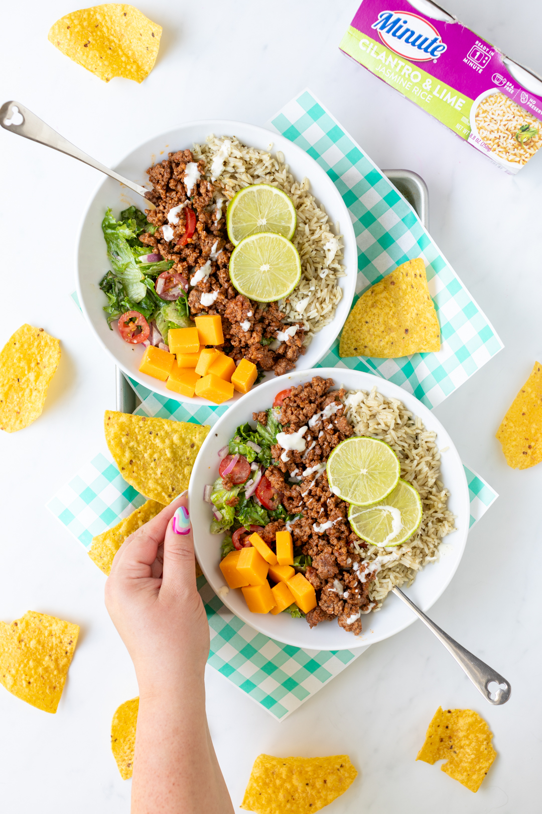 delicious rice bowls with seasoned beef, fresh salad ingredients, lime slices and chunked cheese.