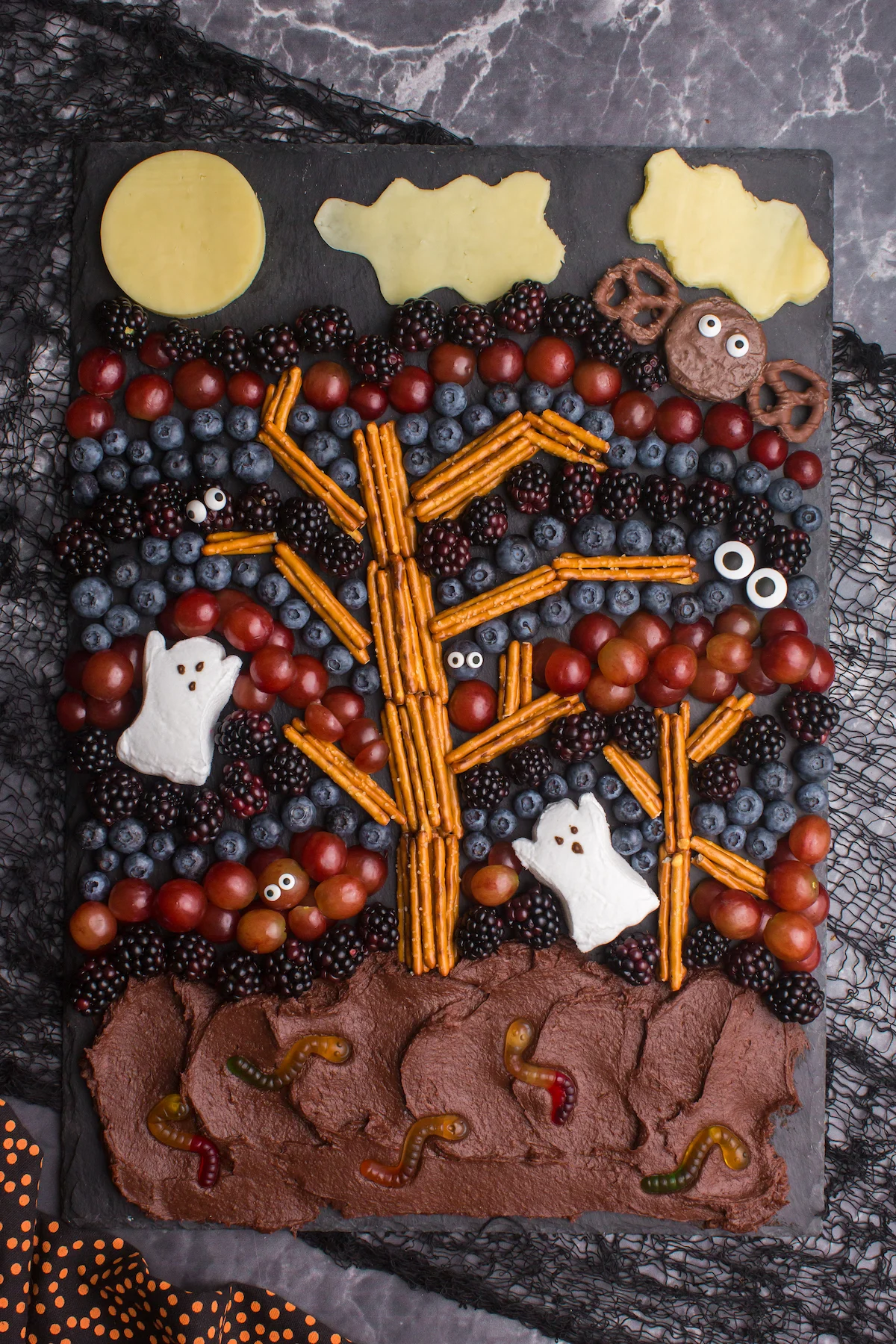 halloween charcuterie board decorated like a spooky forest with fruits.
