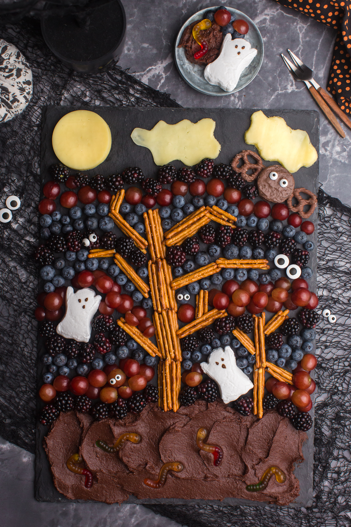 fun halloween dessert board with chocolate frosting, pretzels and fresh fruit