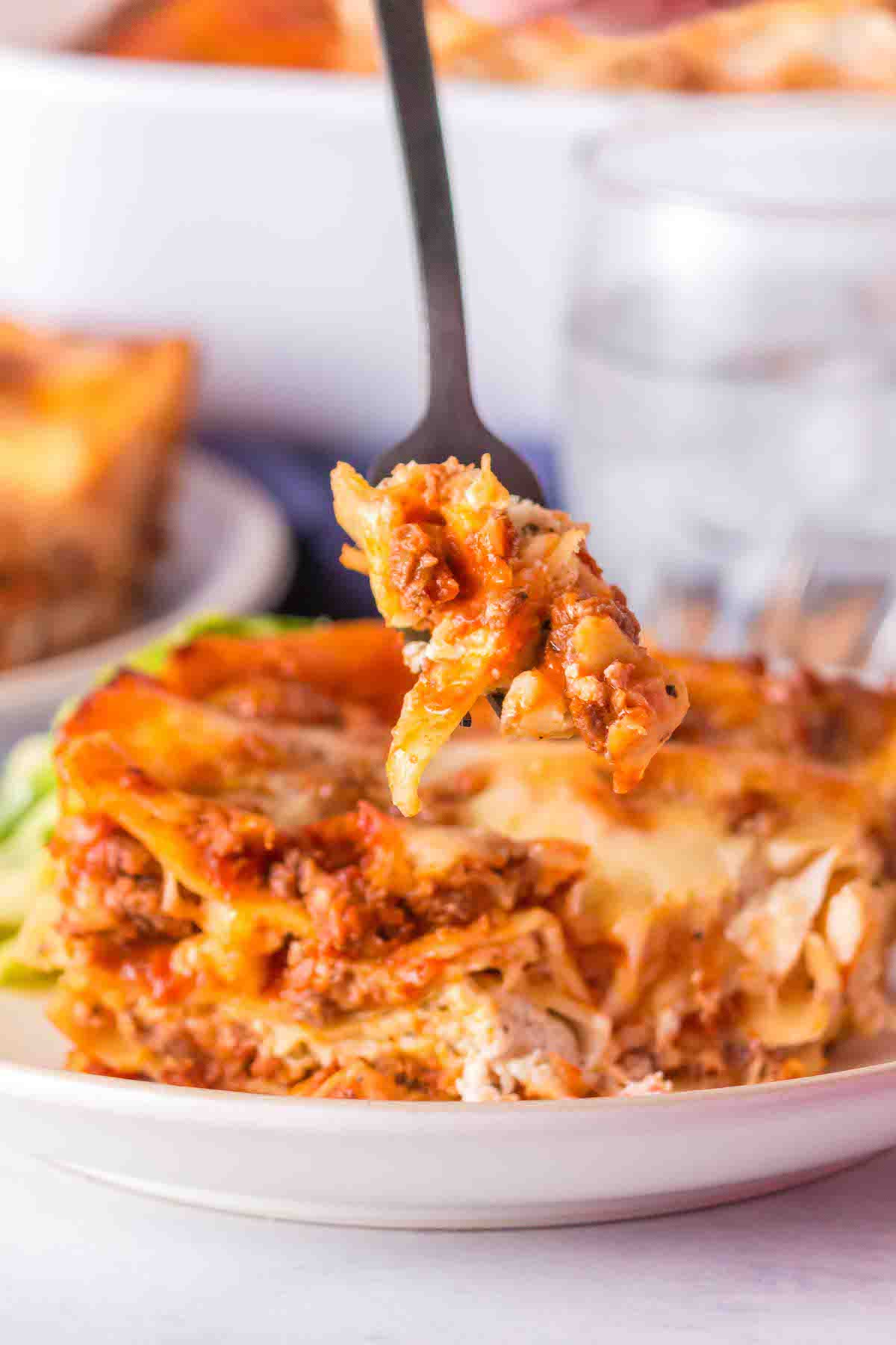 easy lasagna recipe, fork bite of lasagna served on a plate.
