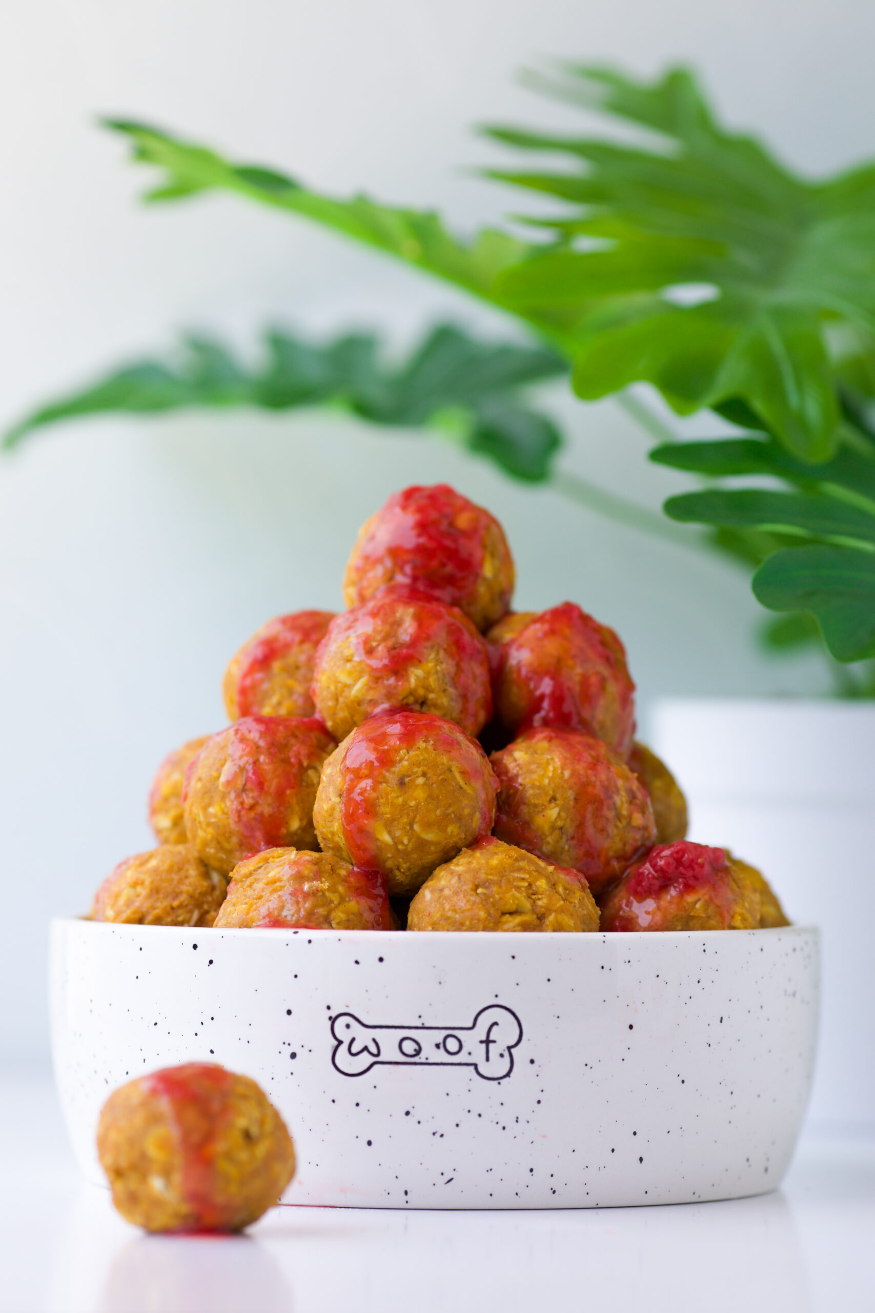 dog treats that look like meatballs with strawberry sauce.