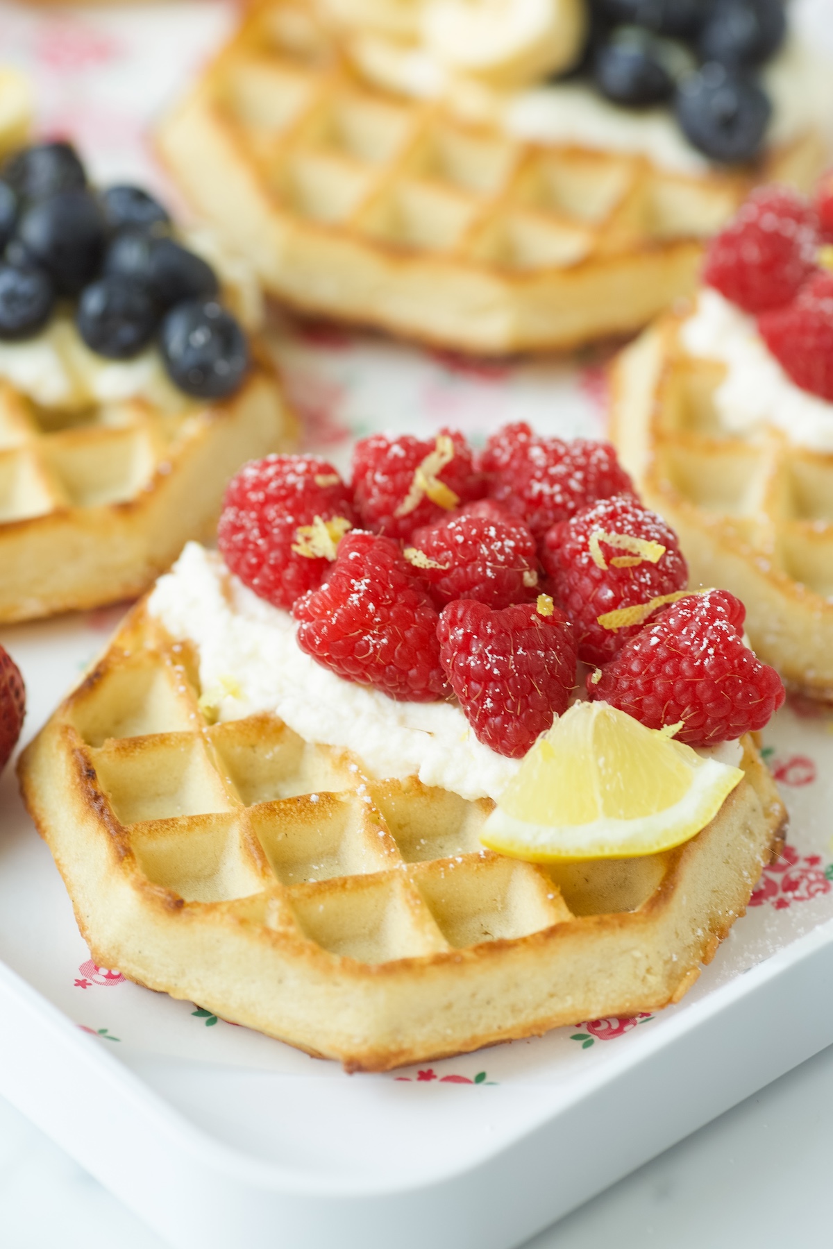 raspberry lemon ricotta waffles with lemon zest and powdered sugar.