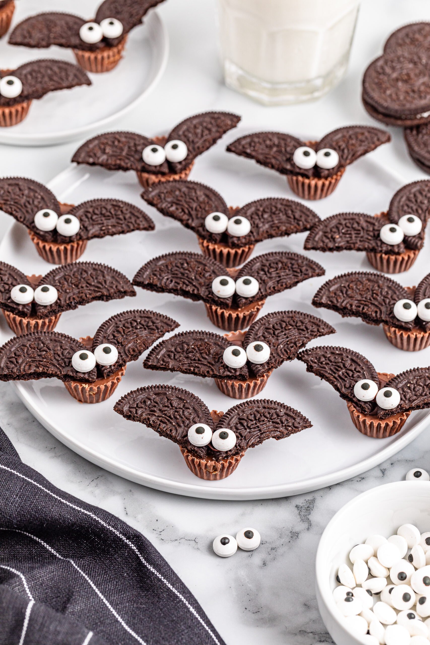 lots of Oreo bat cookies on a white plate