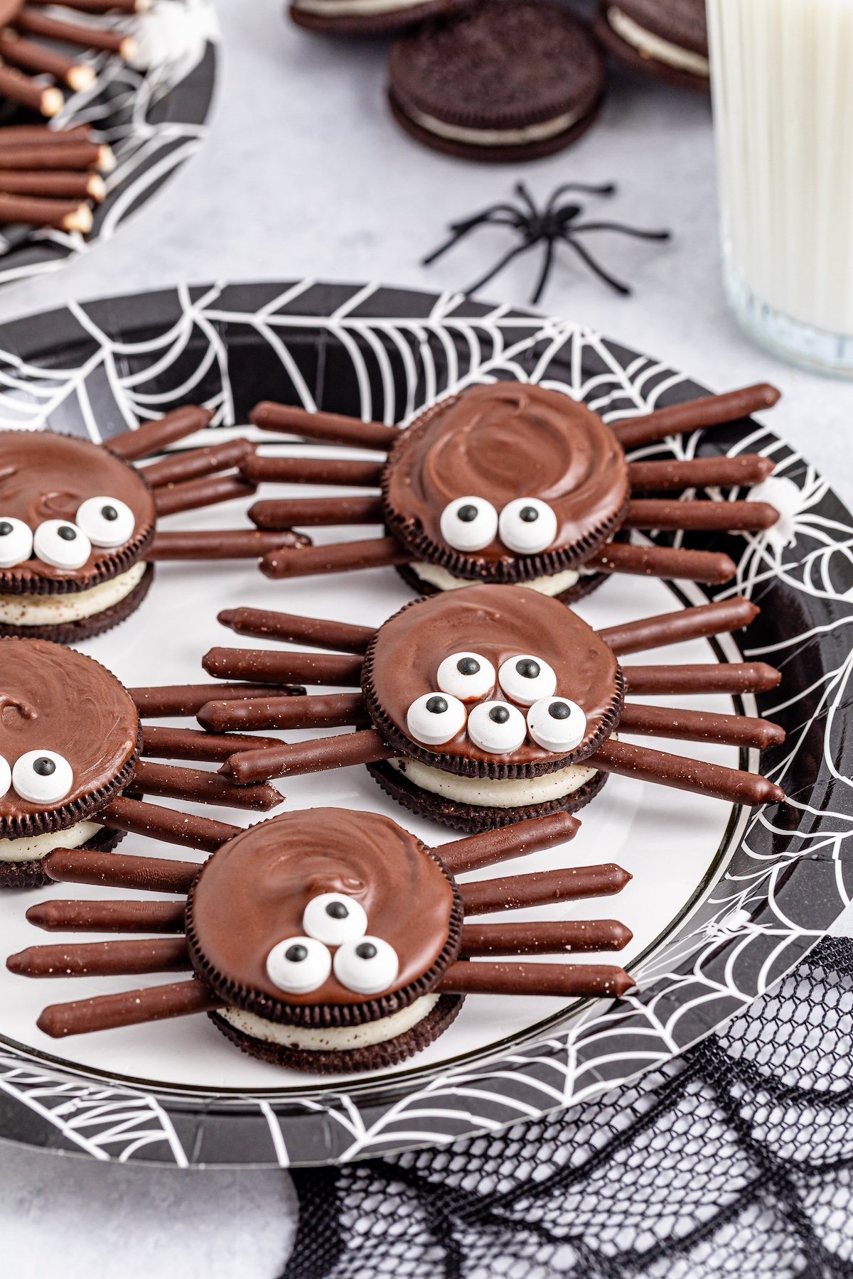 oreo spider cookies on a white plate with webs underneath