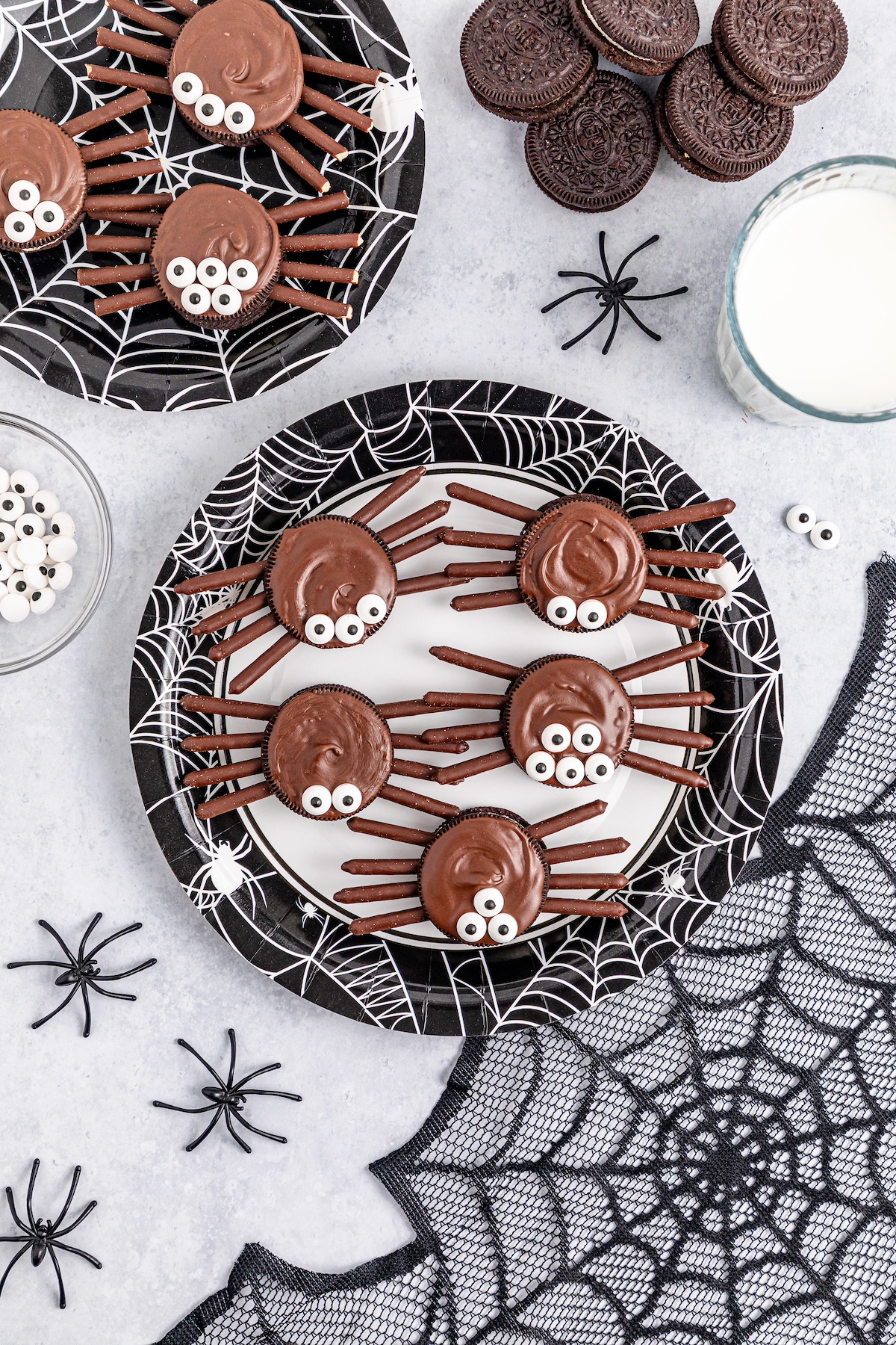 oreo spider cookies on a white plate with webs underneath