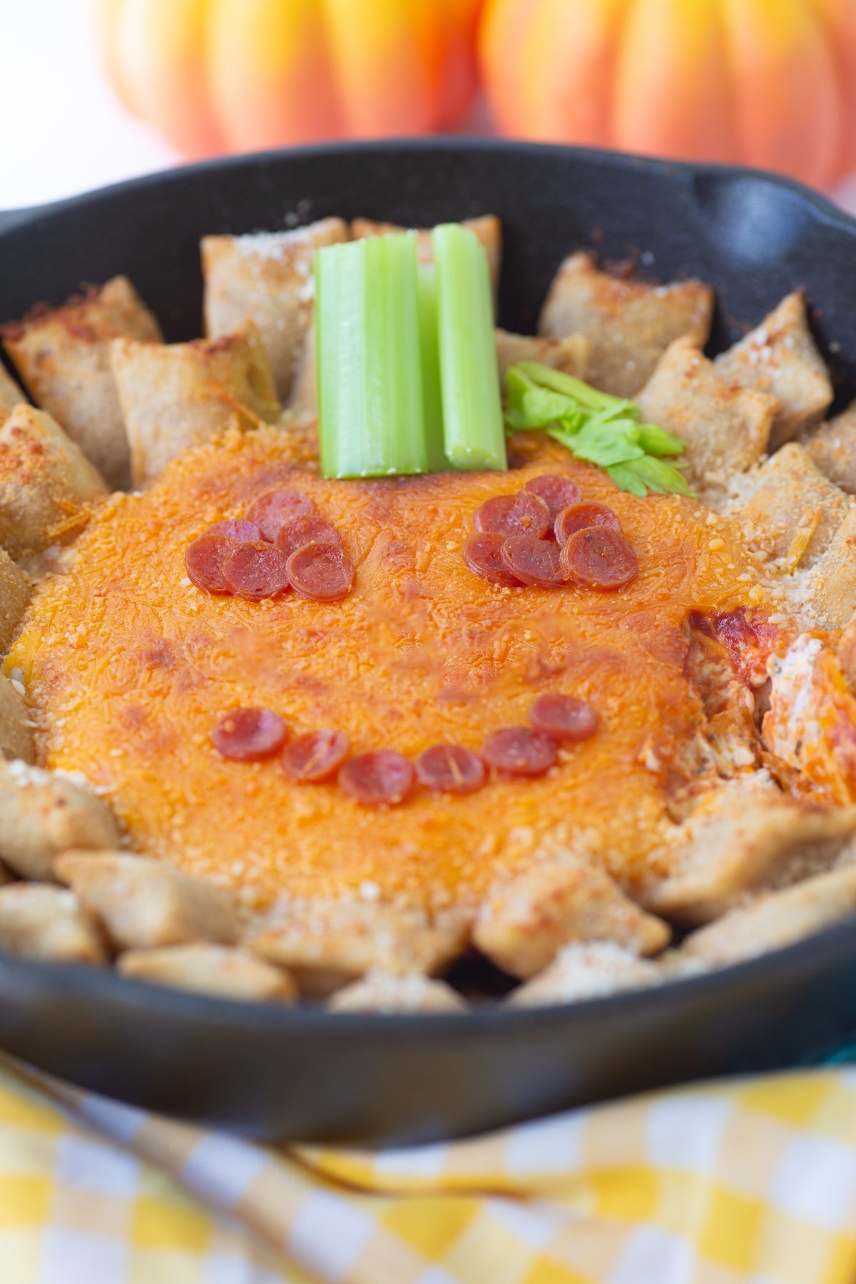 Angled view of Jack-O'-Lantern Dip served with pizza rolls in a skillet.